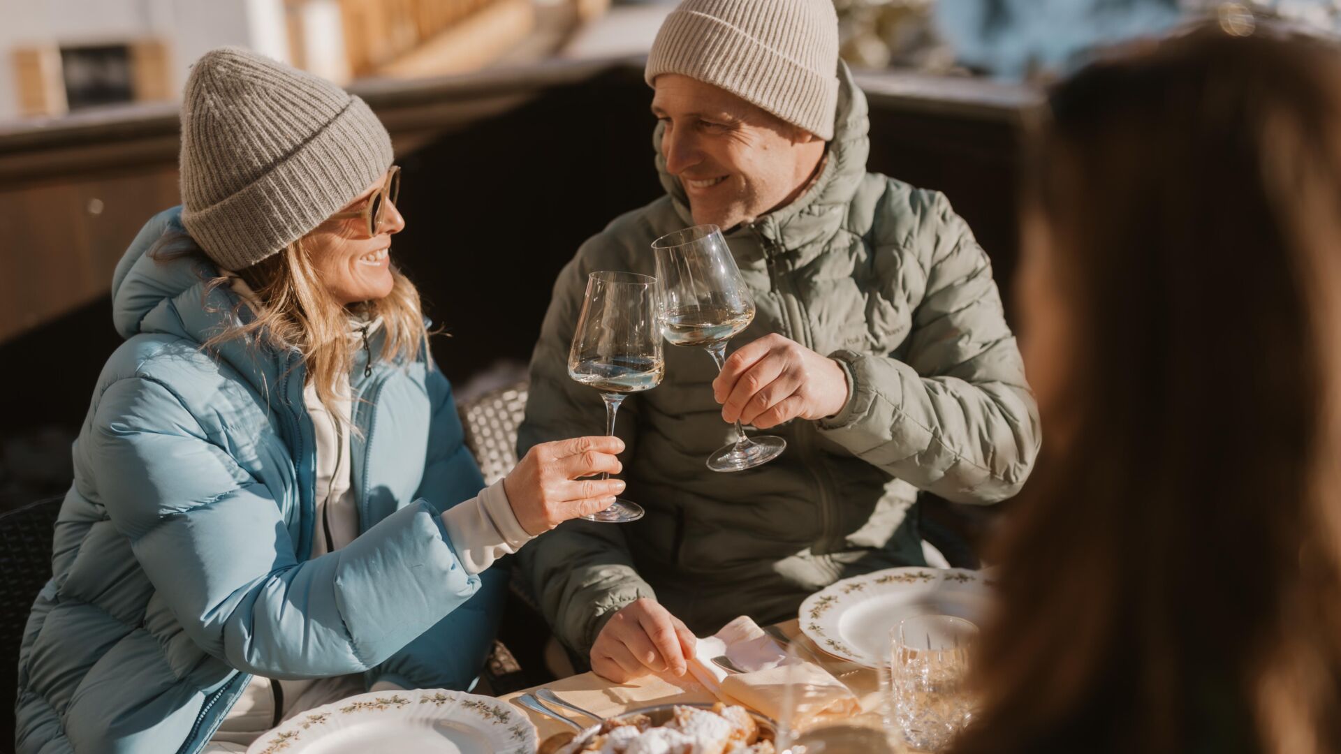 zwei Personen genießen ihren Skitag auf der Sonnenterrasse in Lech Zürs am Arlberg mit einem Glas Weißwein
