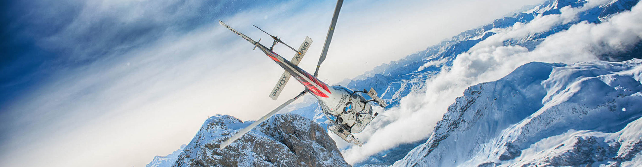 Blick auf einen Hubschrauber, der über die verschneiten Berge am Arlberg fliegt