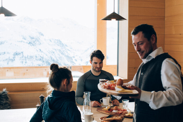 Ein Kellner bringt eine Frühstücksplatte zu den Gästen an den Tisch