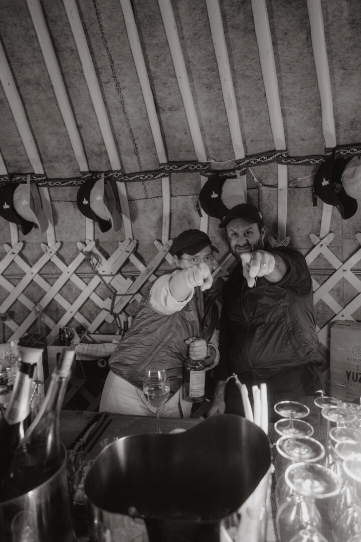 zwei Personen zeigen indieselbe Richtung während sie gerade verschiedene Getränke mischen