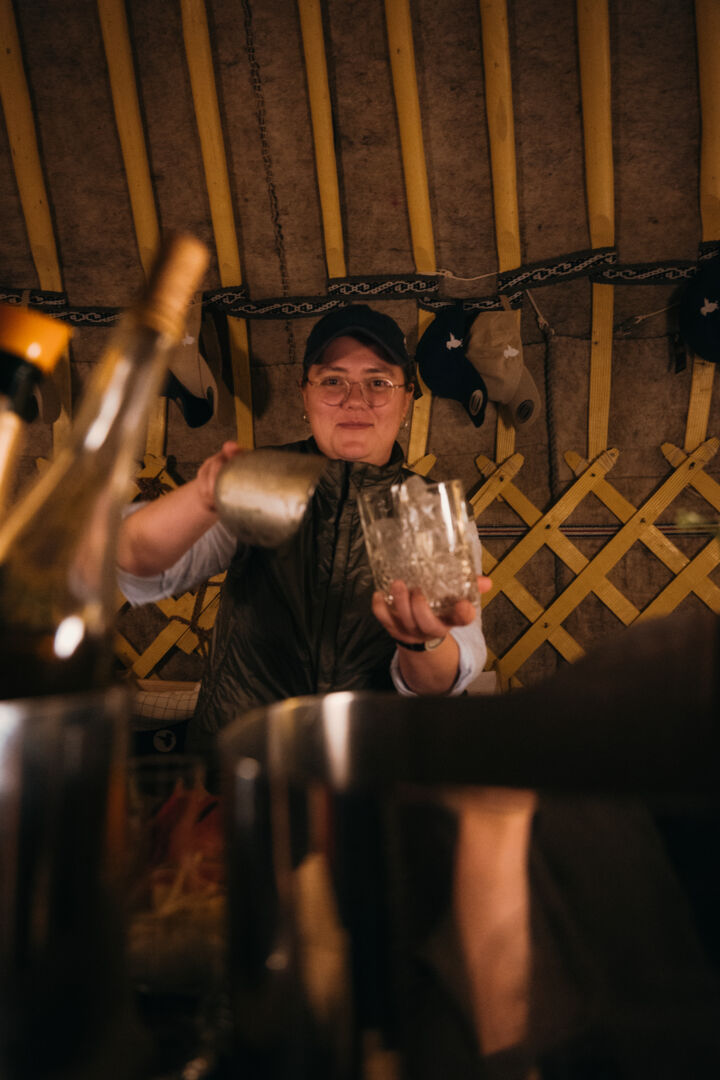 eine Barkeeperin füllt die Getränke aus dem Shaker in die Gläser