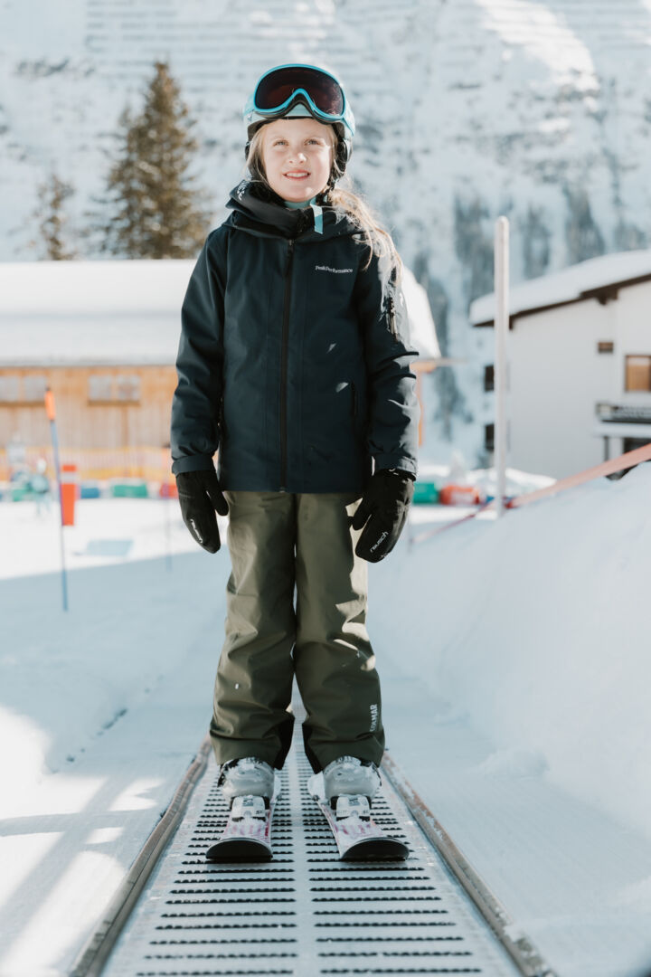 Kind steht strahlend auf dem Förderband am Weg nach oben