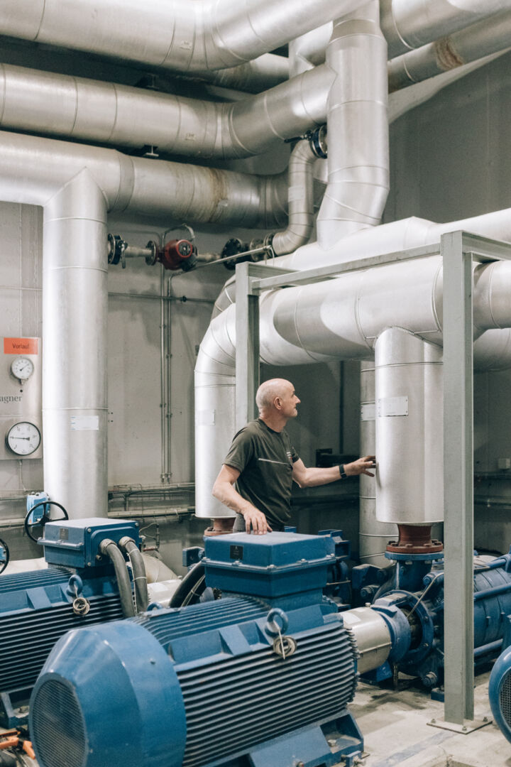 Ein Arbeiter im Biomasseheizwerk Lech vor den Leitungsrohren stehend