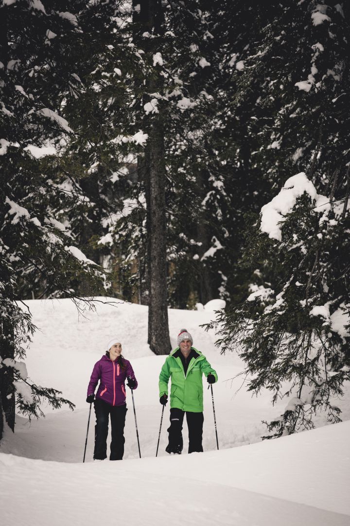 zwei Personen genießen die traumhafte Schneelandschaft beim Winterwandern durch die Wälder von Lech Zürs