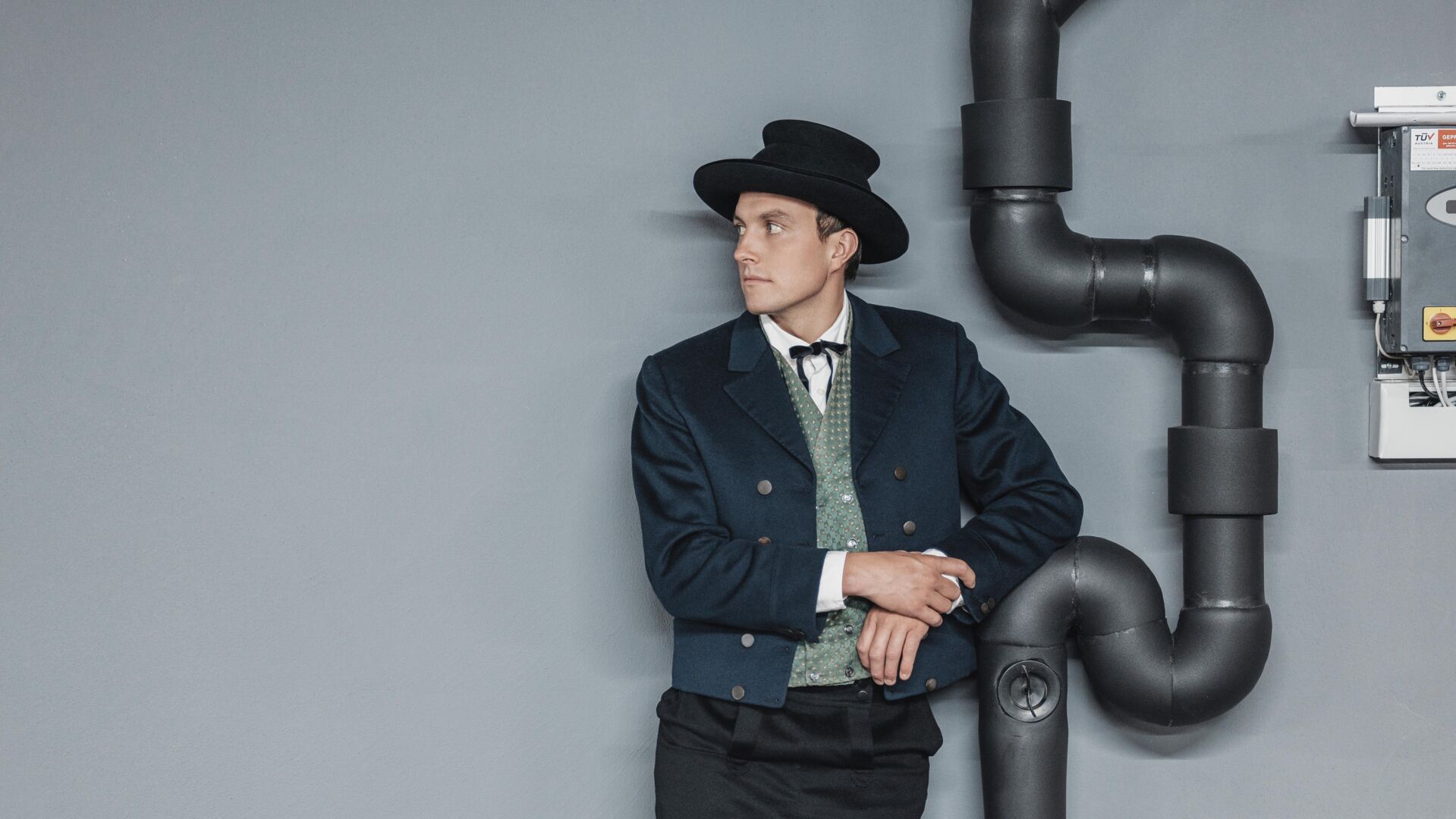 Mann in Walser Tracht mit schwarzen Hut, gruenes Gelee, blauer Blazer, Hose bis zu Knien und weißen Stutzen