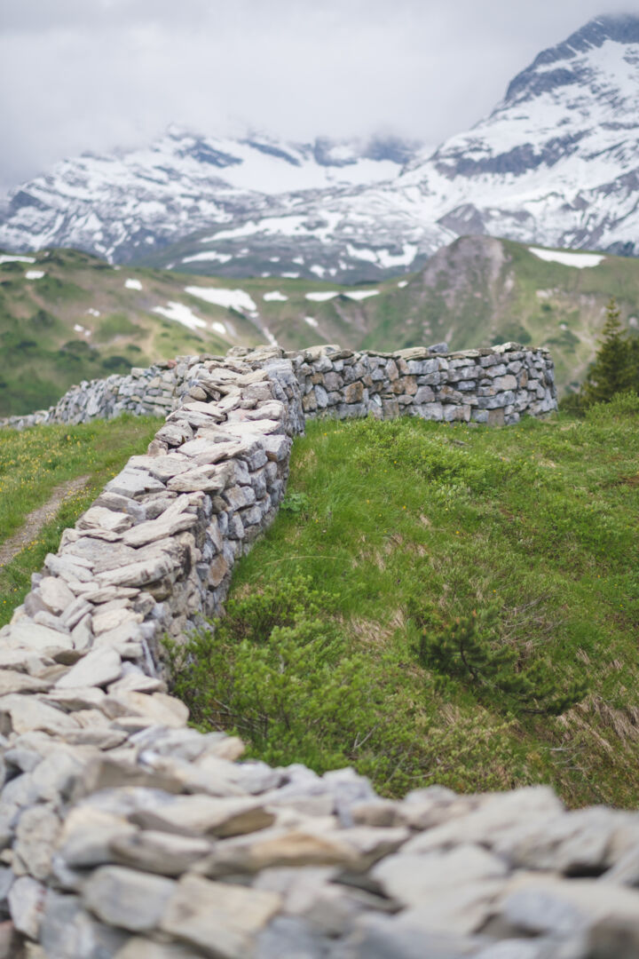 Steinmauer mit verschneiten Gipfeln im Hintergrund
