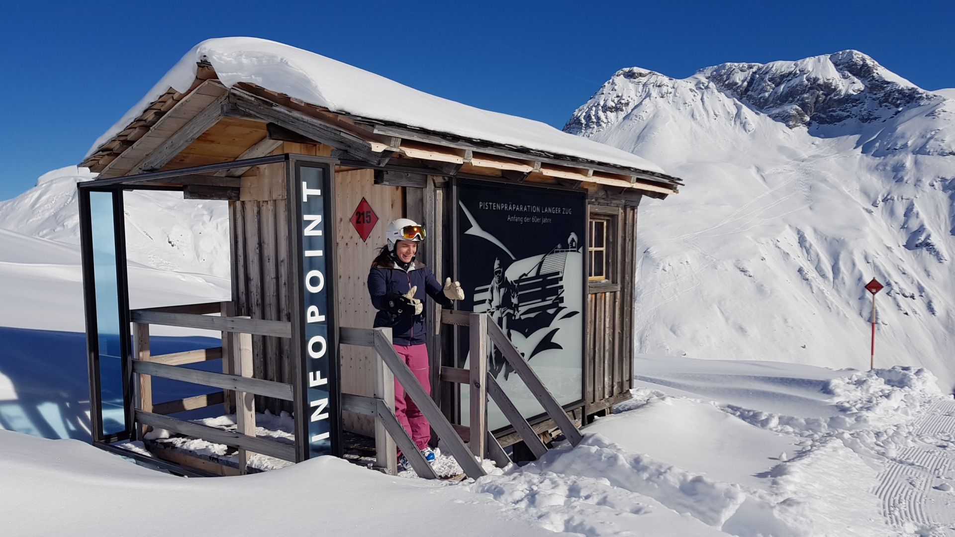 eine Skifahrerin steht vor dem Infopoint Langer Zug