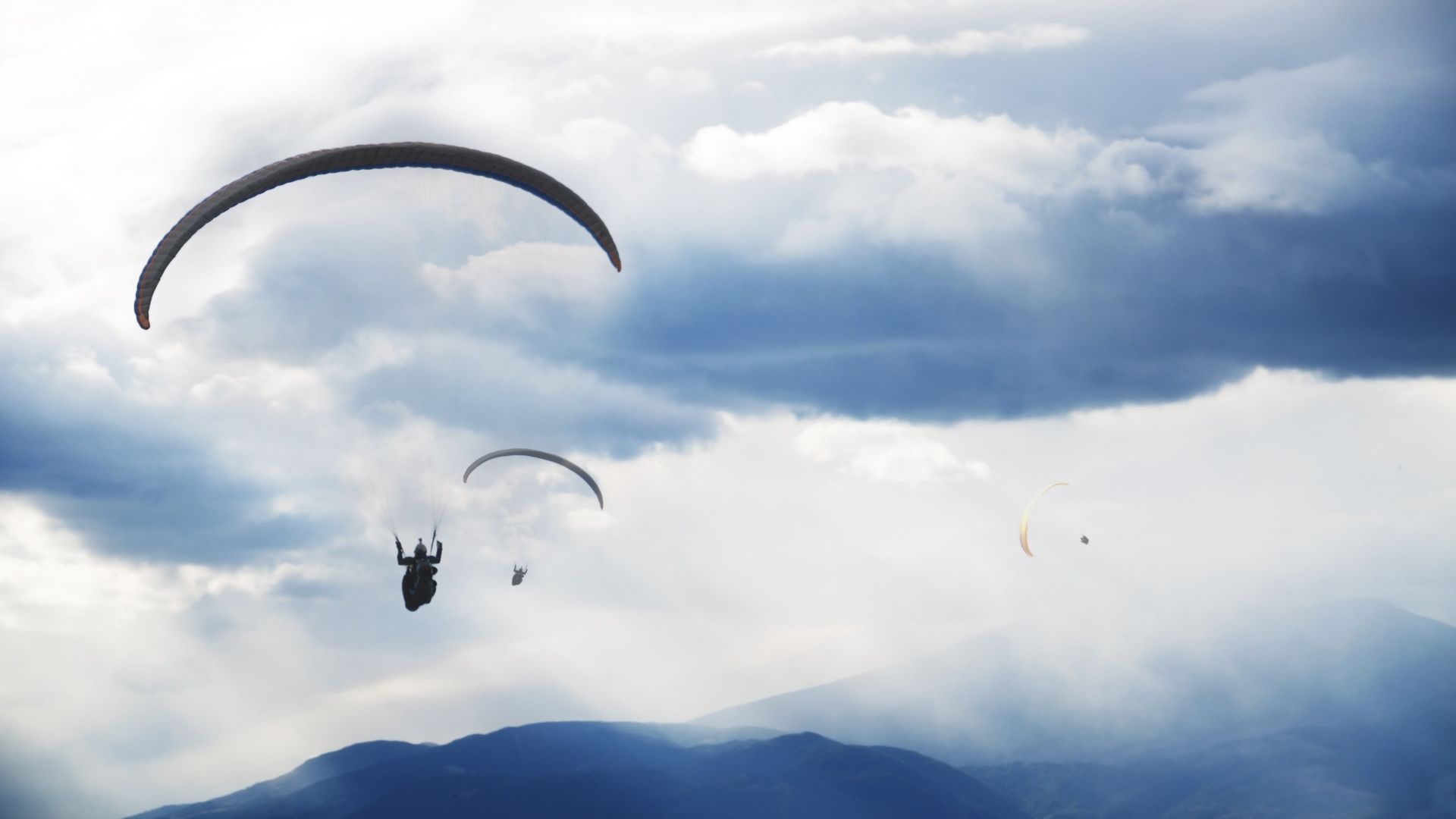 mehrere Tandemflieger fliegen durch die Wolkendecke