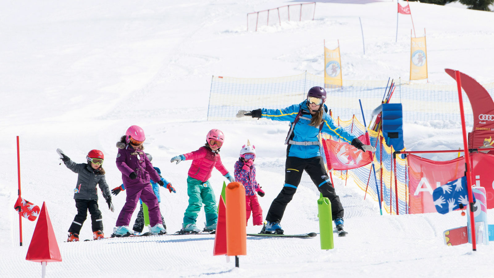 eine Skilehrerin bringt den Kindern das Skifahren im Kinderland bei