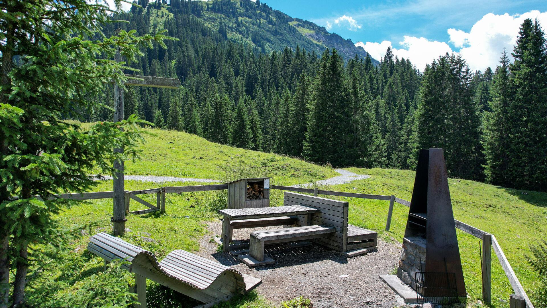 Grillplatz in Stubenbach umringt von grünen Wiesen und hohen Bäumen