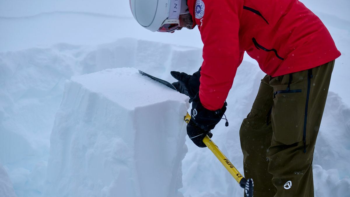 ein Mann in Skiausrüstung macht eine Schneedeckenprofilanalyse 