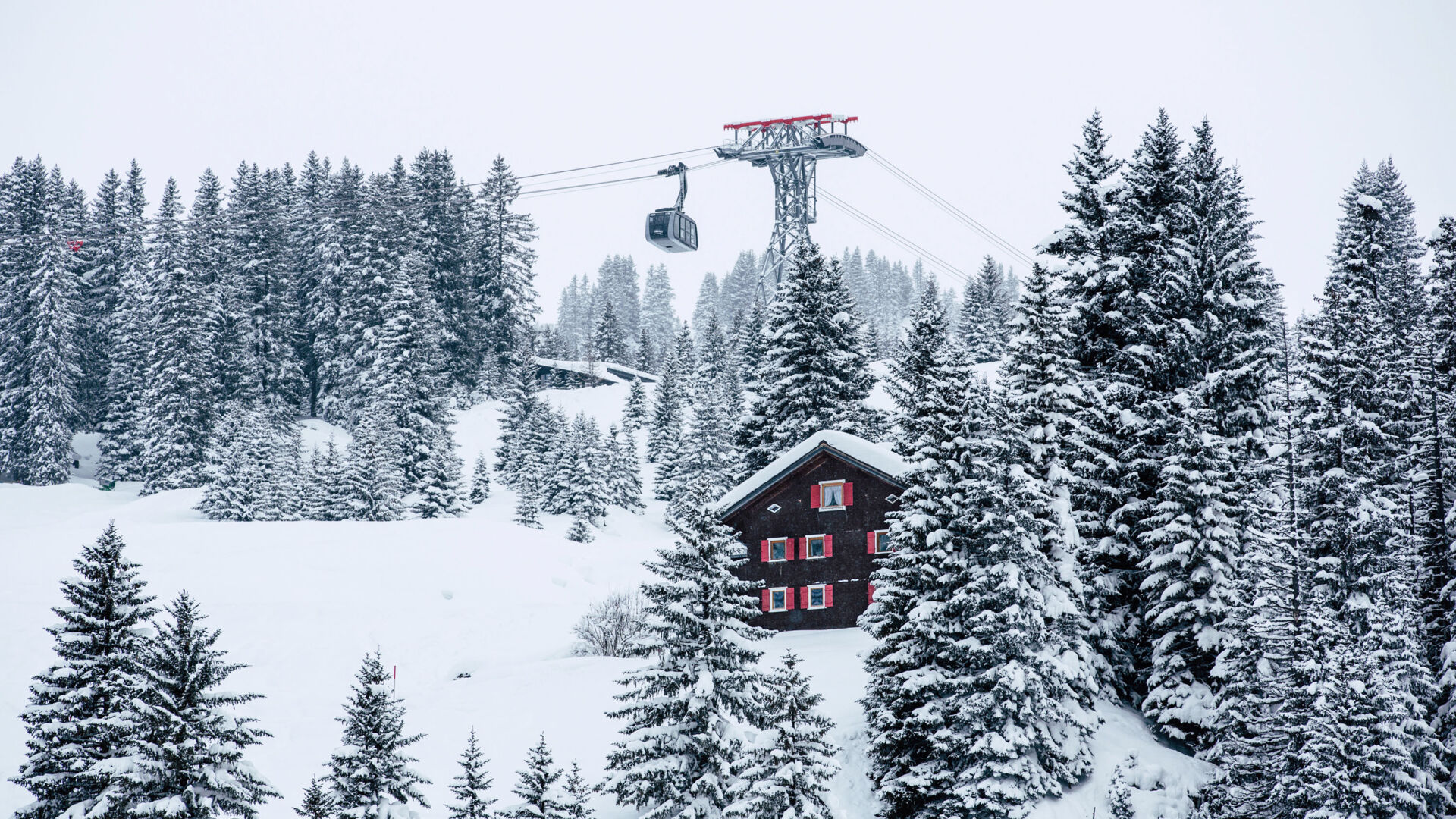 Blick auf eine verschneite Berglandschaft mit der Bergbahn nach Oberlech im Hintergrund im Winter