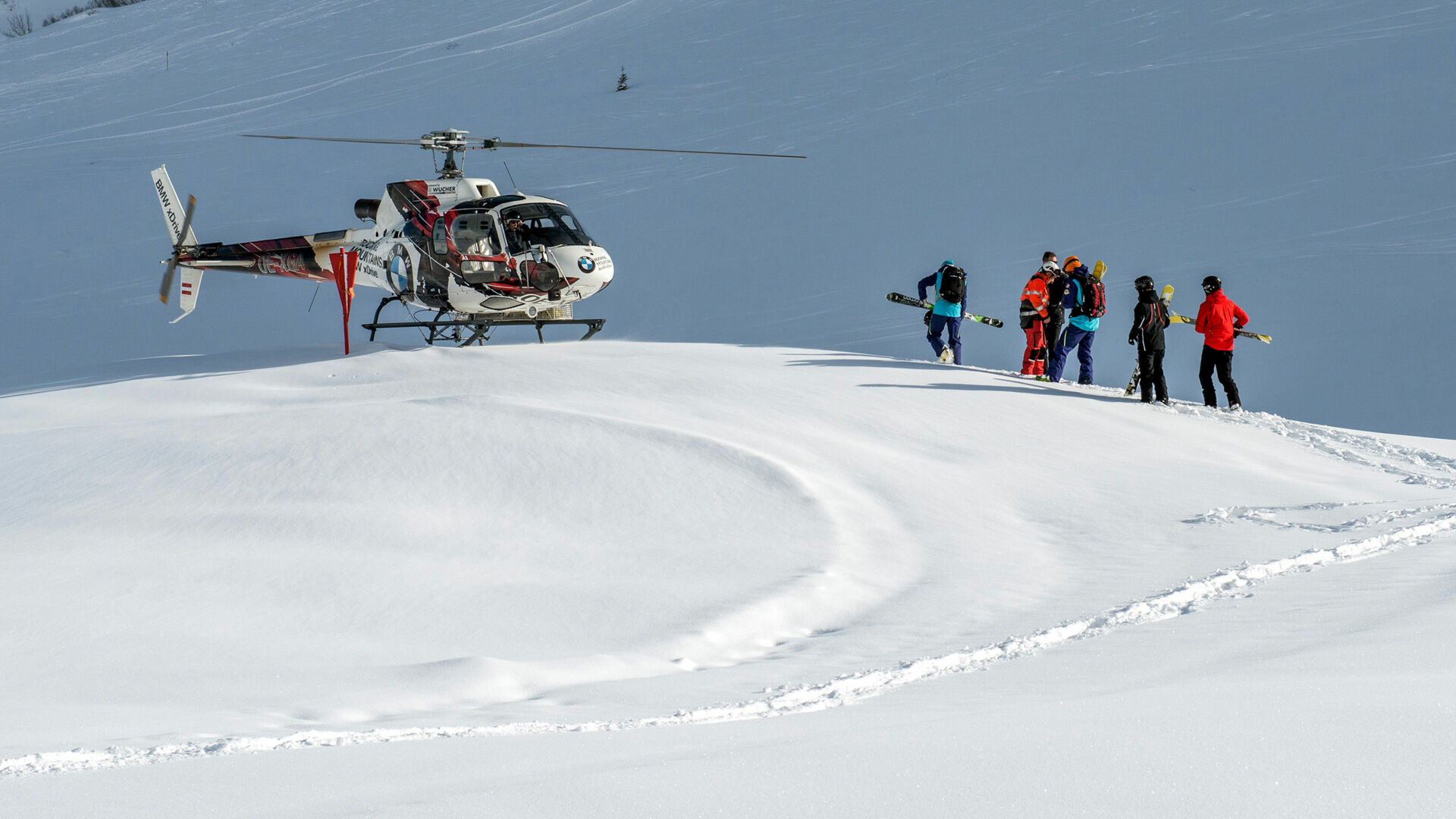 eine Gruppe von Skifahrern geht zum Hubschrauber und macht sich auf den Weg zum traumhaften Heliskiing in Lech Zürs