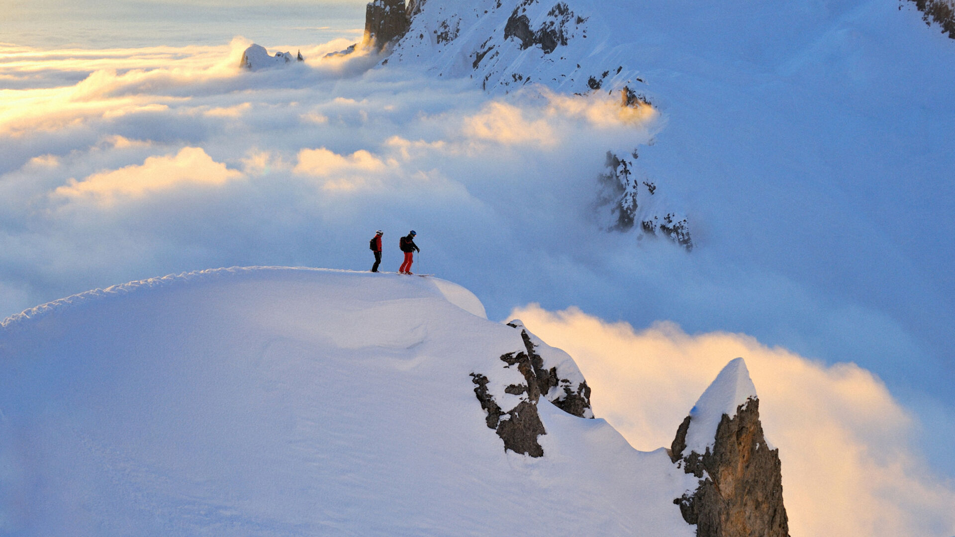 zwei Freerider stehen am Abhang des Berges und genießen die traumhafte Aussicht auf den frischen Puderschnee