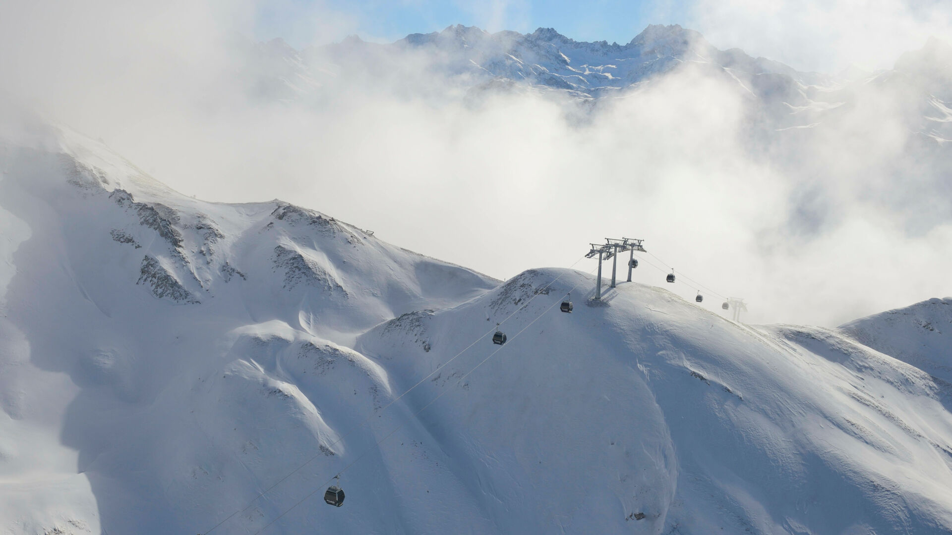Blick auf die Flexenbahn, inmitten der verschneiten Berglandschaft, die vom Nebel eingehüllt ist