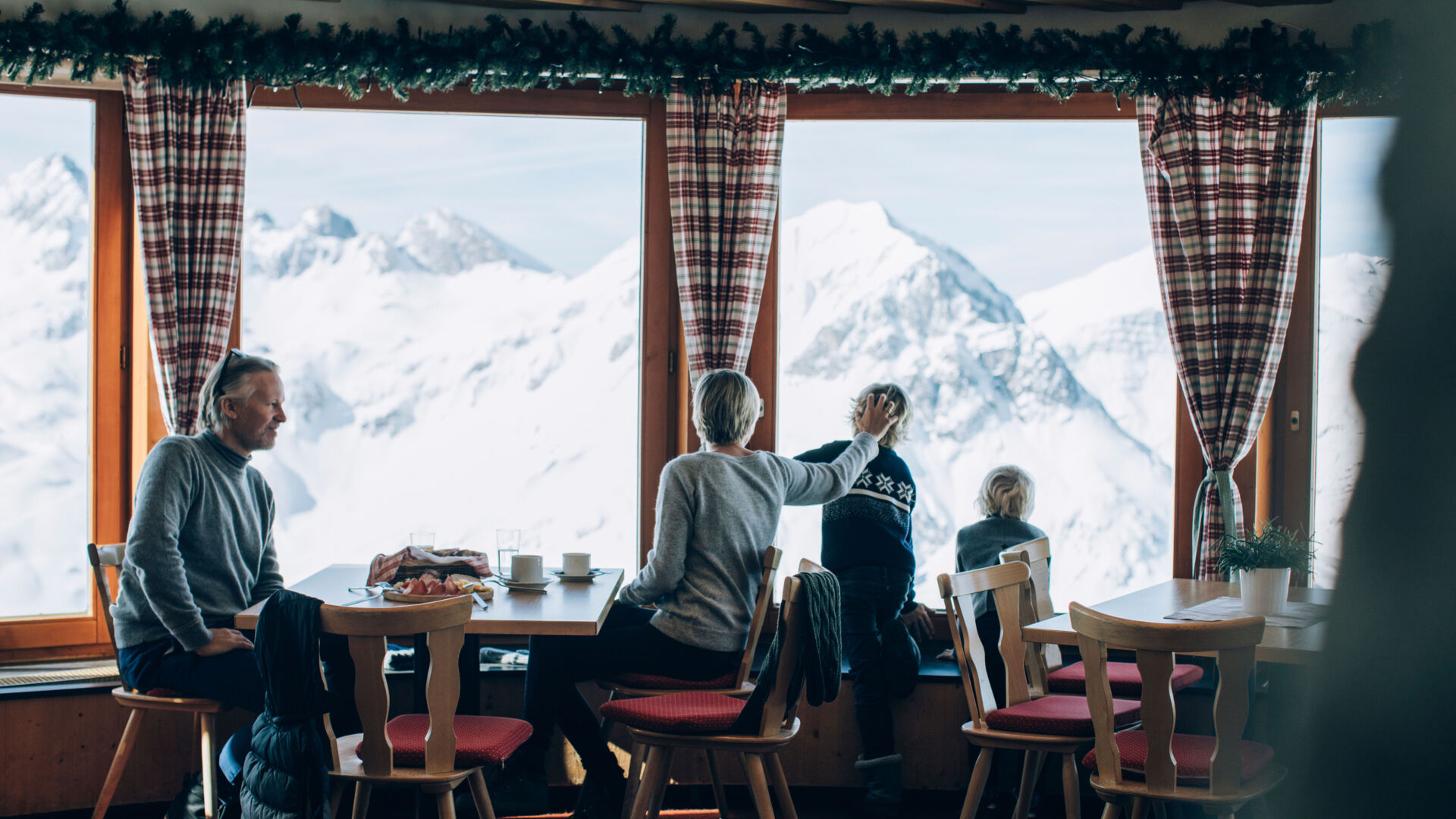 einige Personen genießen die Kulinarik und die winterliche Aussicht in Lech in Vorarlberg beim Einkehren