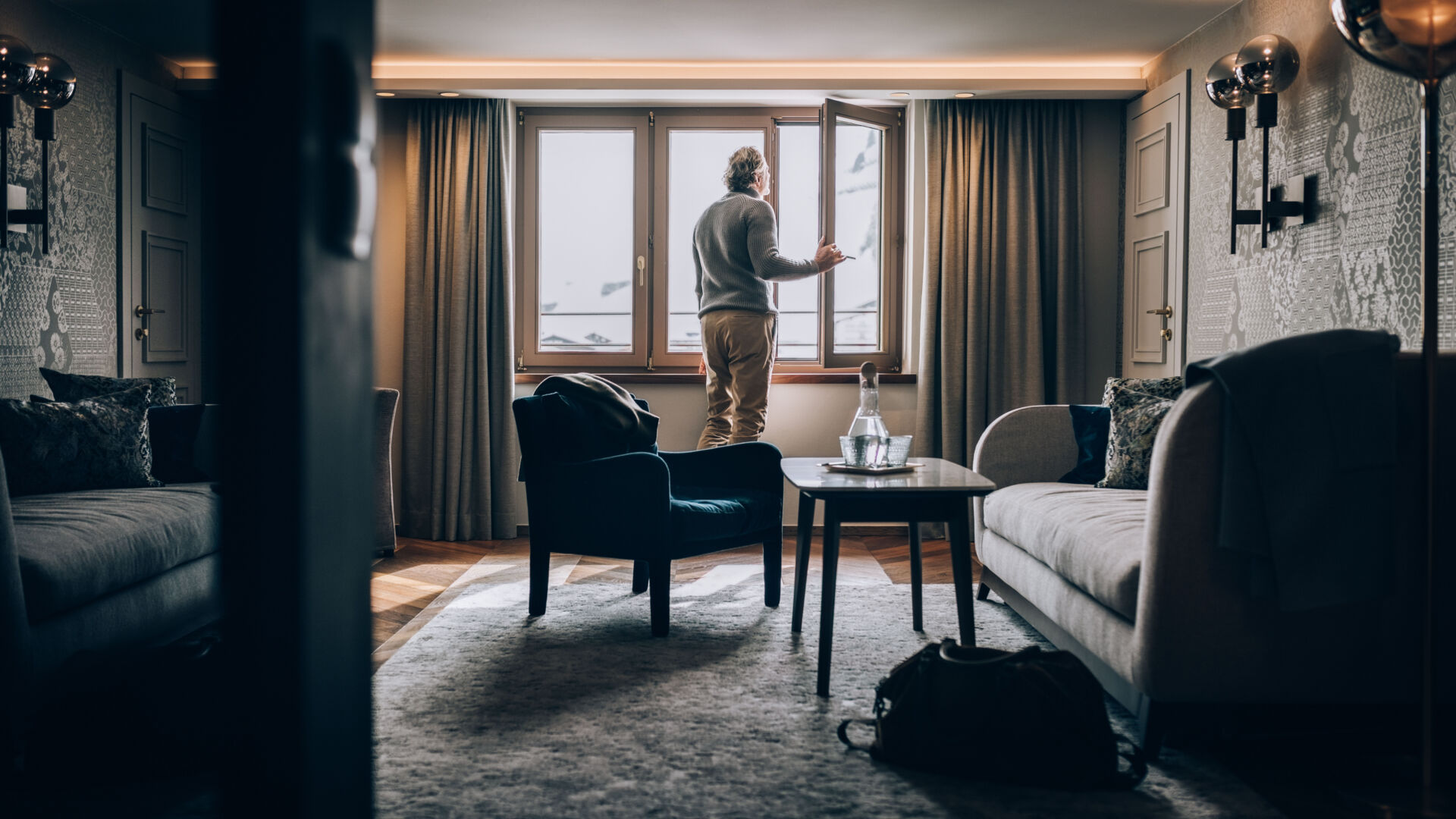 eine Person schaut aus dem Fenster eines Hotelzimmers hinaus