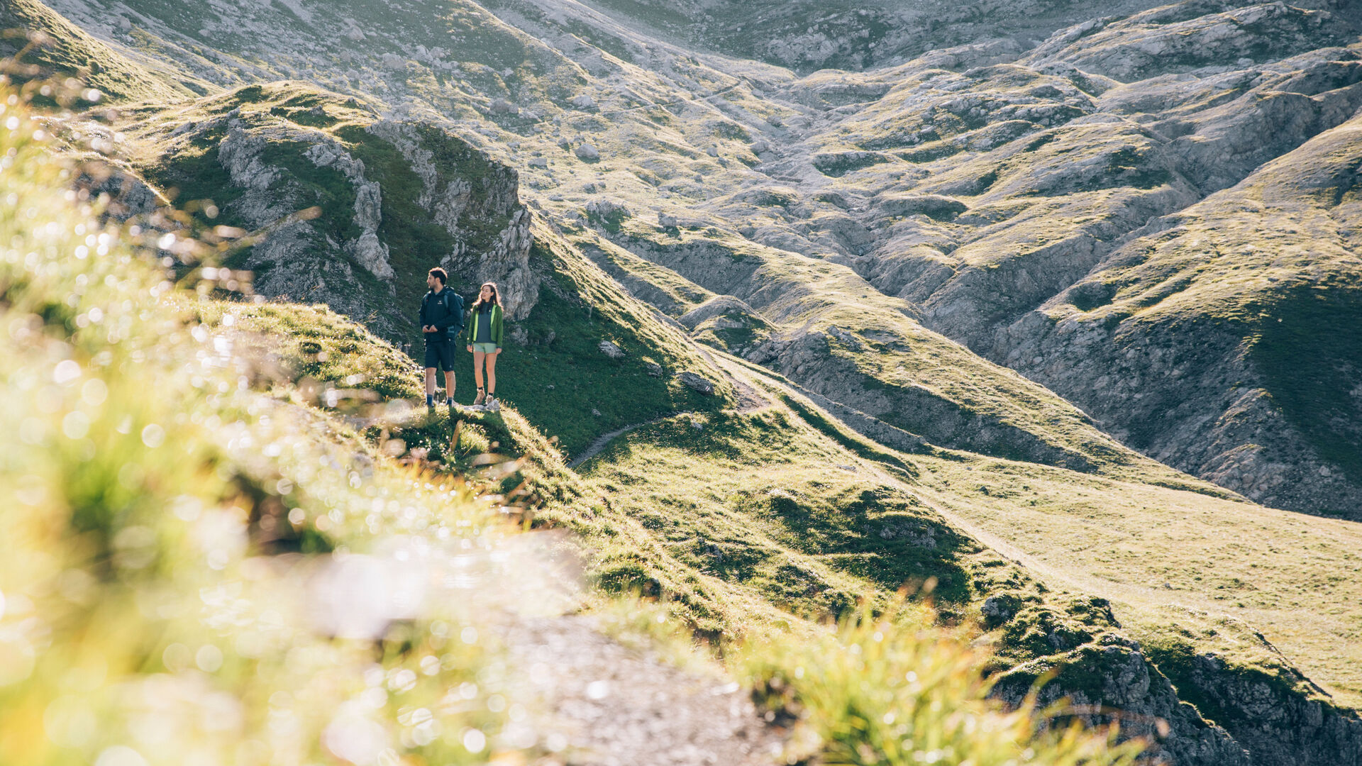 Wanderpärchen geht auf einem Steig im Sonnenstein mit einer imposanten Gebirgslandschaft im Hintergrund