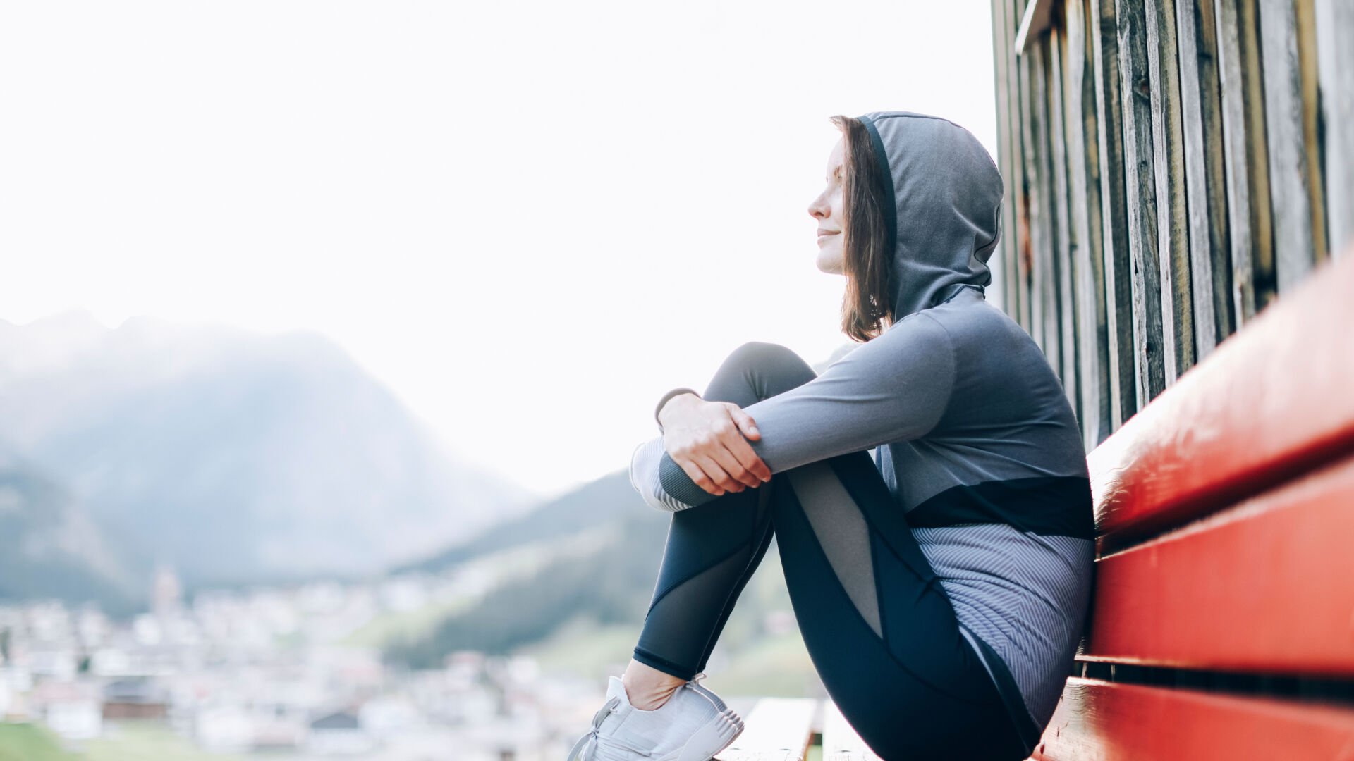 Eine Joggerin sitzt auf einer Bank und hält einen Moment inne um durchzuatmen