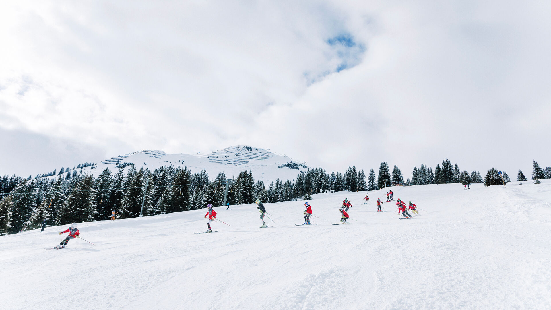 Skiclubkinder fahren hintereinander die Piste hinunter