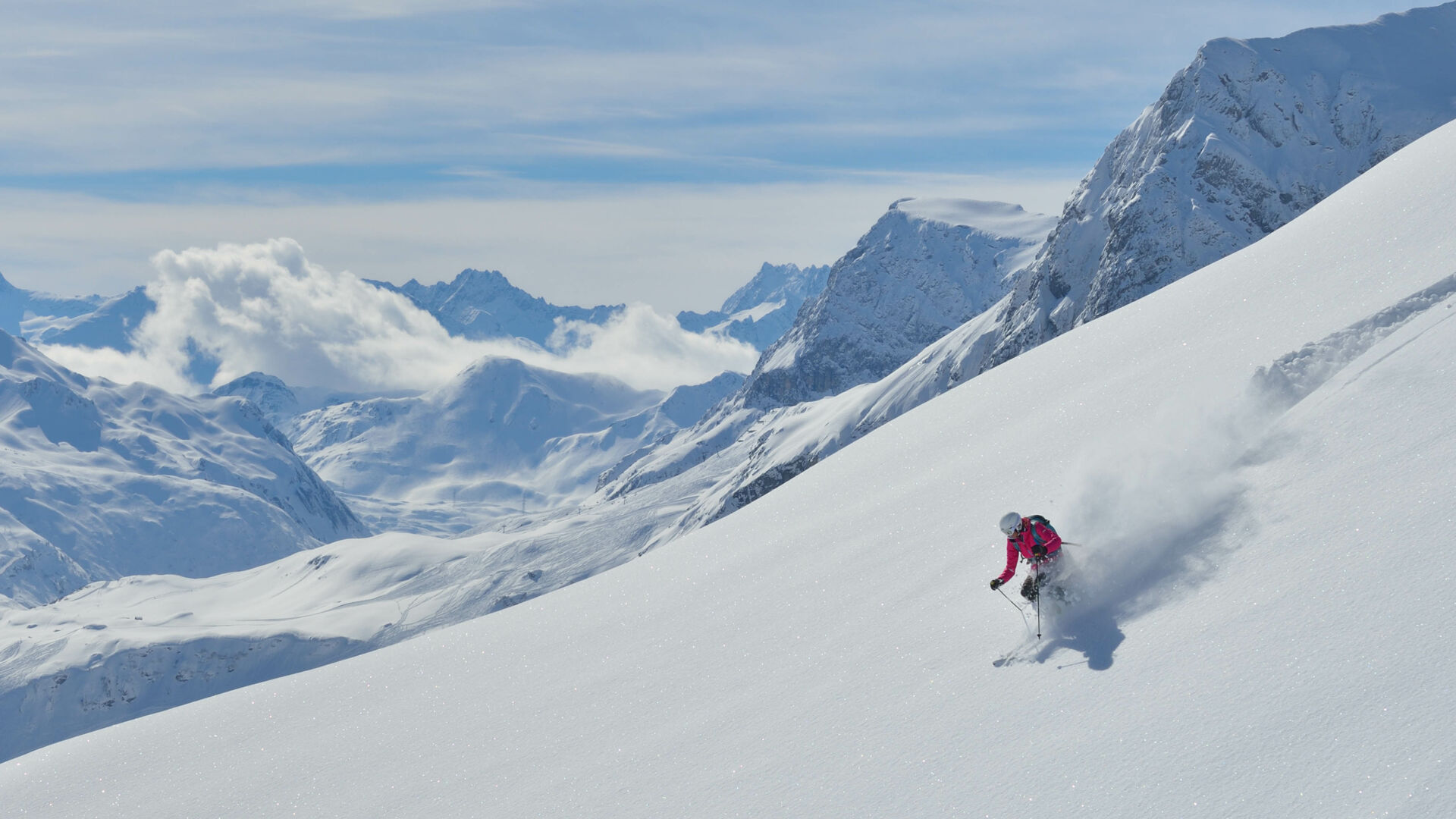 Eine Skifahrerin fährt den offenen Hang im Backcountry des Arlbergs alleine hinab
