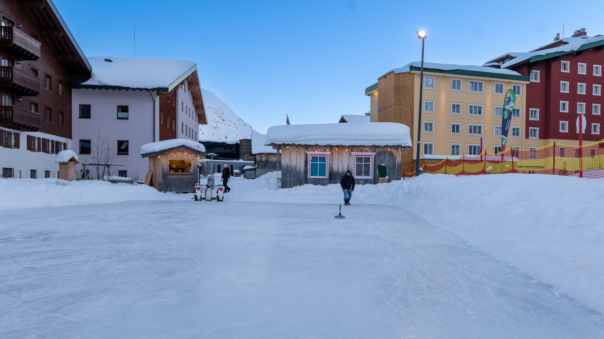 Blick auf den Eislaufplatz in Zürs mit dem winterlichen Ortsbild im Hintergrund