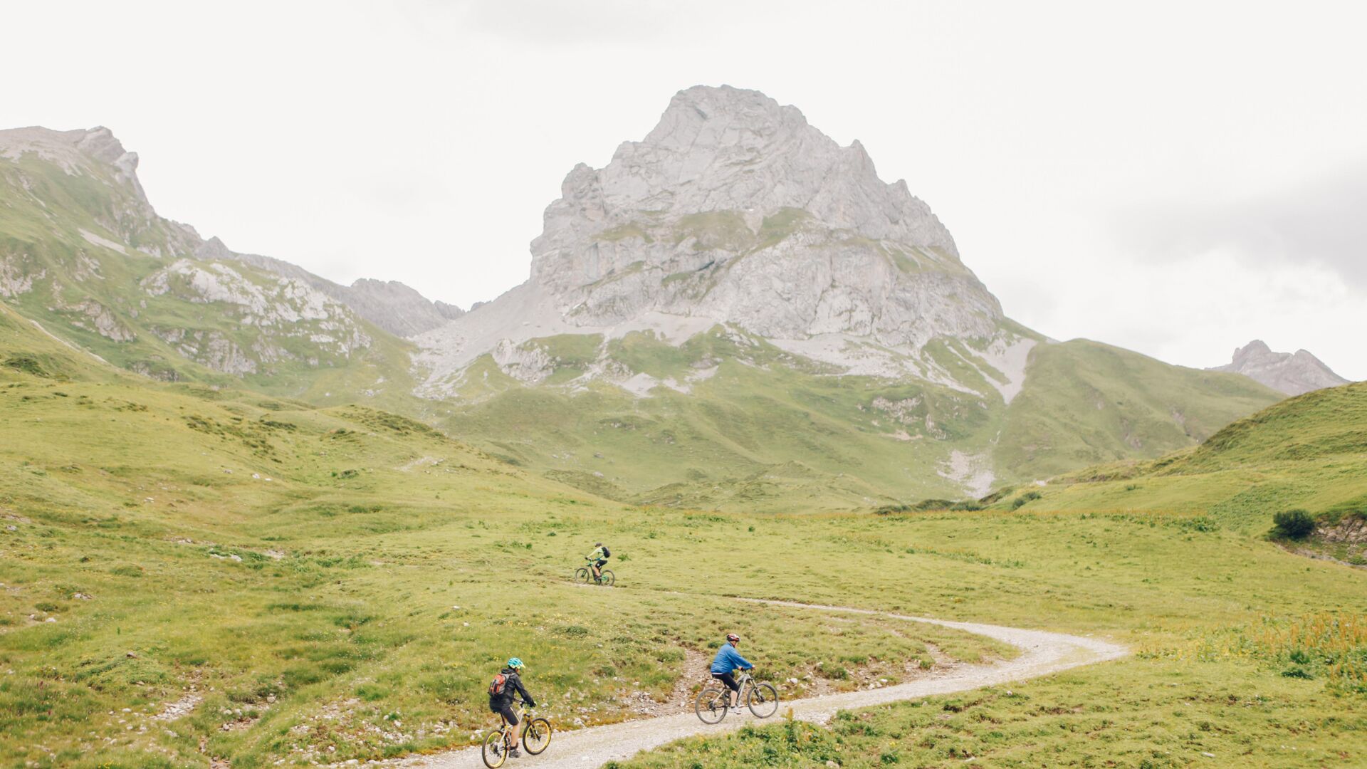 Drei Radfahrer fahren einen Schotterweg auf einen Berg hinauf. 