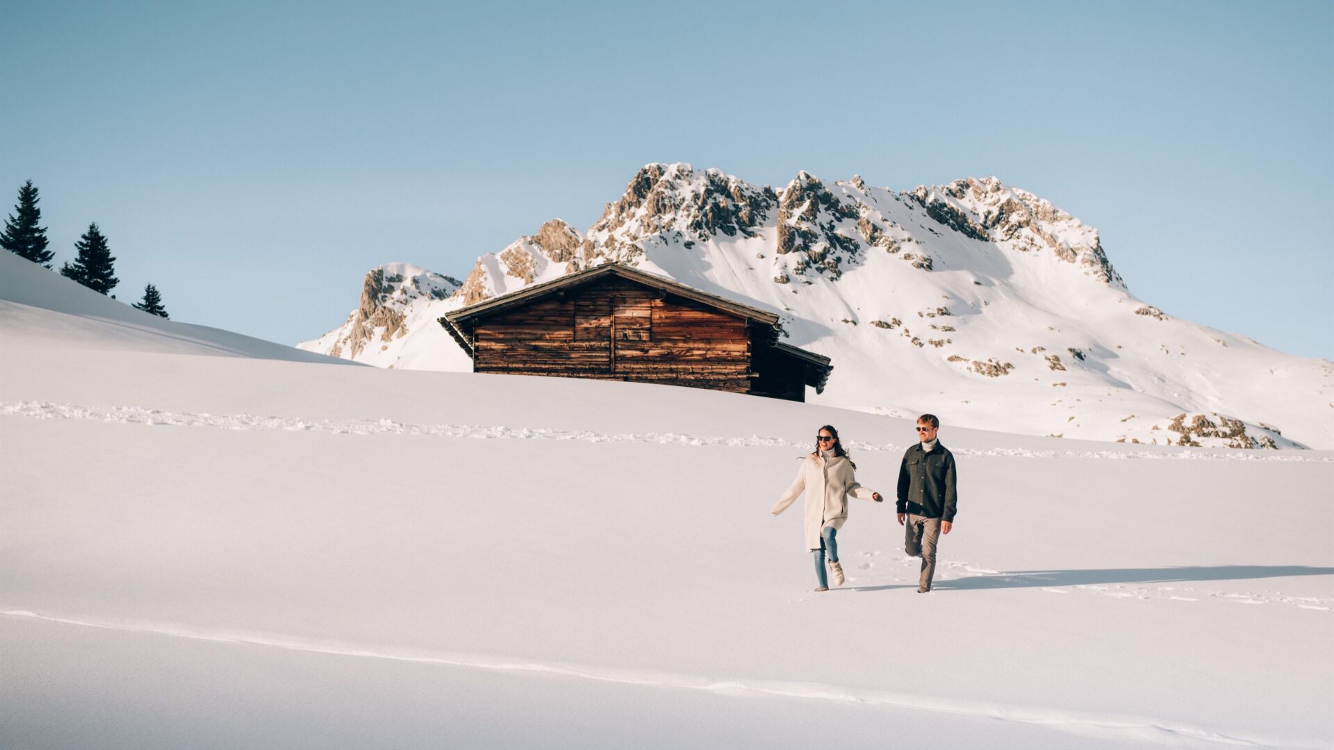 Mann und Frau beim Spazieren im Schnee vor Berg
