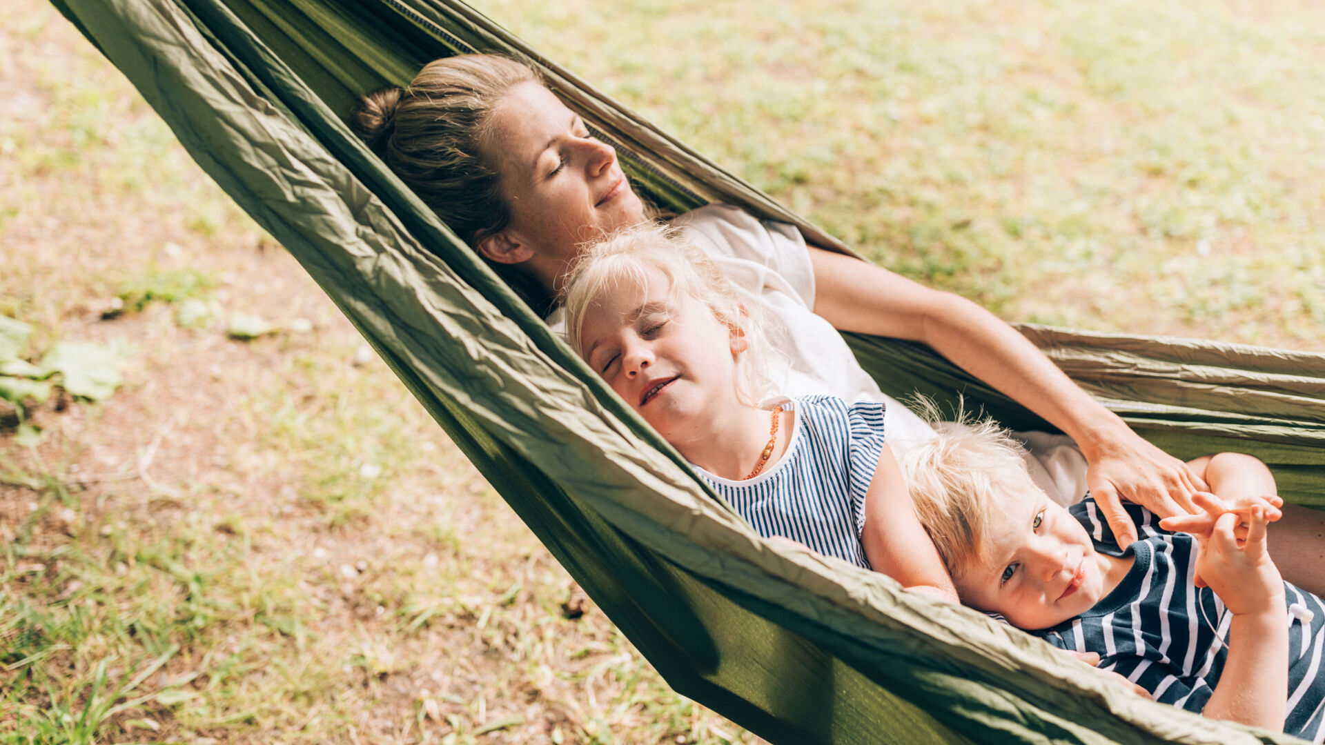 Eine Mutter beim Entspannen mit ihren Kindern in der Haengematte