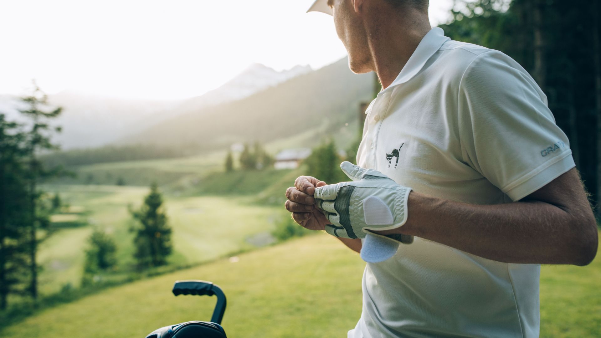 Golfer zieht sich den Golfhandschuh an für den nächsten Schlag und blickt in die Ferne