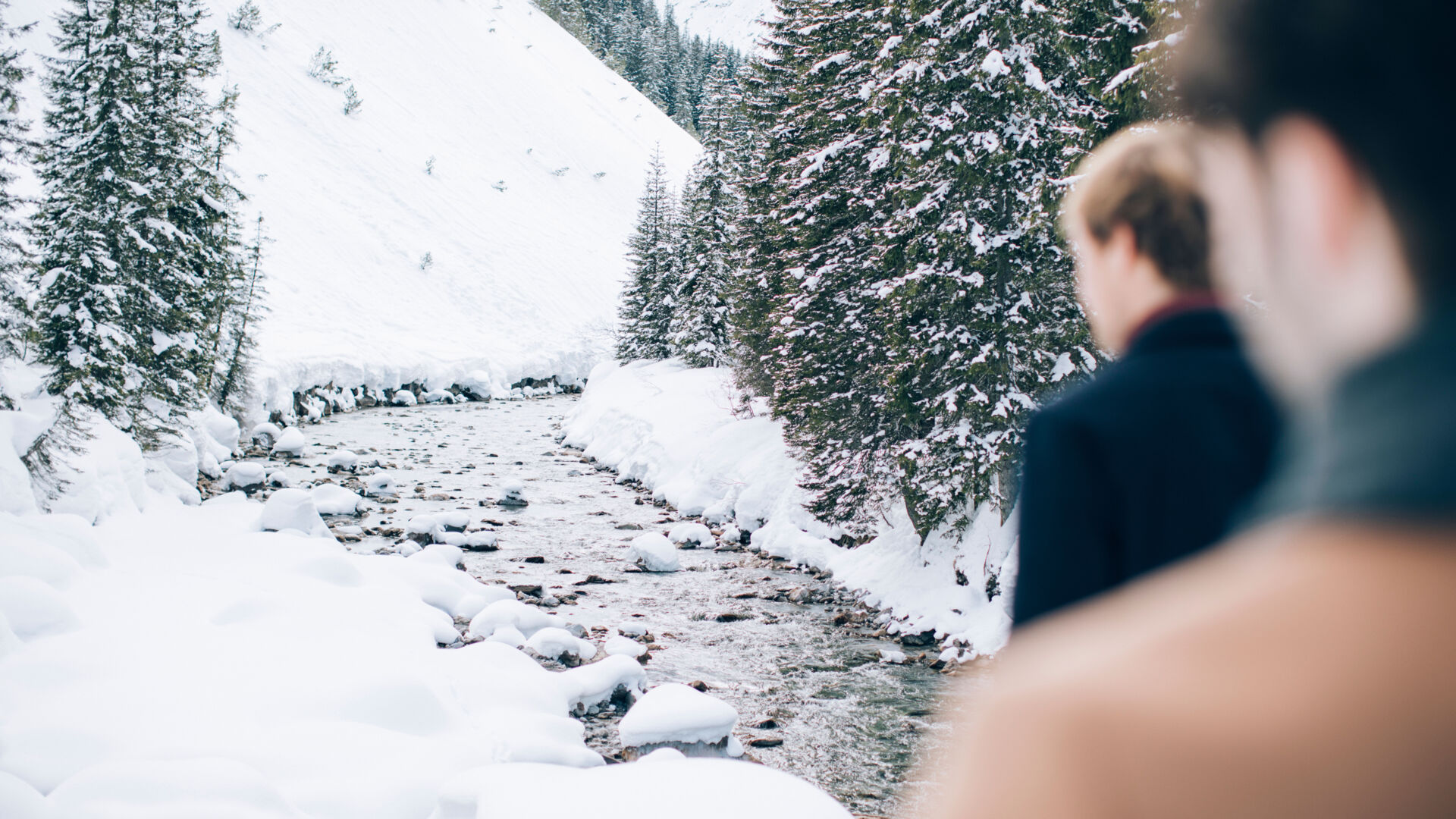 zwei Männer laufen beim Winterwandern am verschneiten Fluss Lech vorbei
