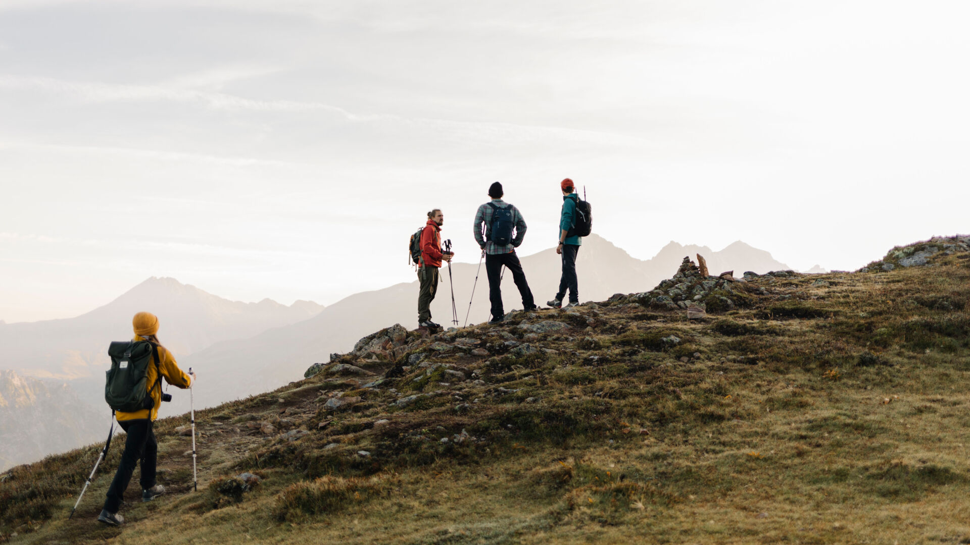 Vier Wanderer stehen am Gebirgsgrat und genießen den Panoramablick