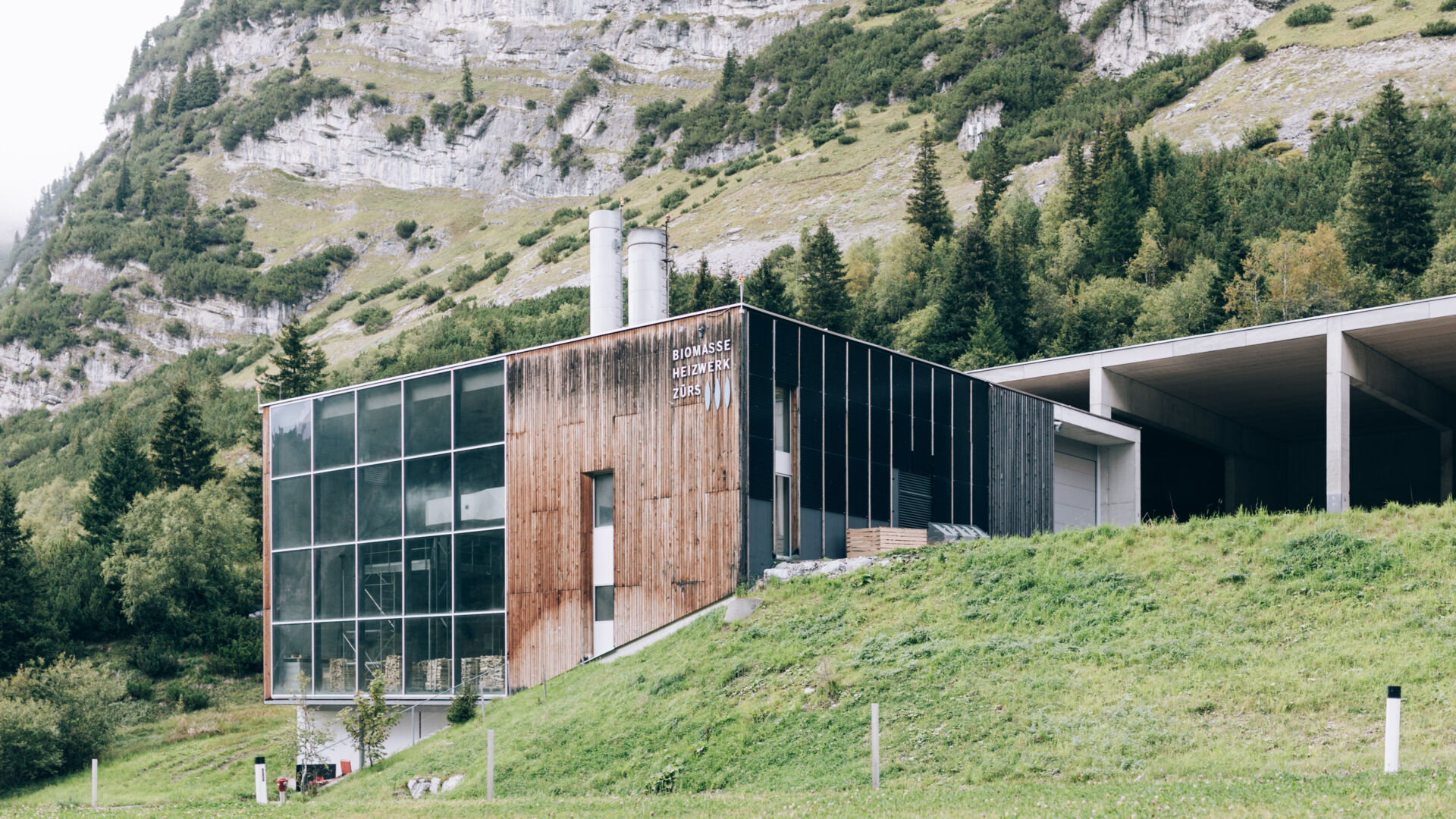 Biomasseheizwerk Zürs Holzgebäude mit Glasfassade und anschließender Garage für die Holzschnippsel, lokalisiert zwischen Lech und Zürs lokalisiert