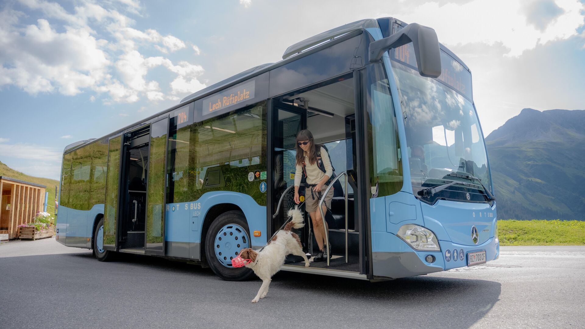 Frau steigt mit Hund an der Leine aus dem Ortsbus Lech aus.