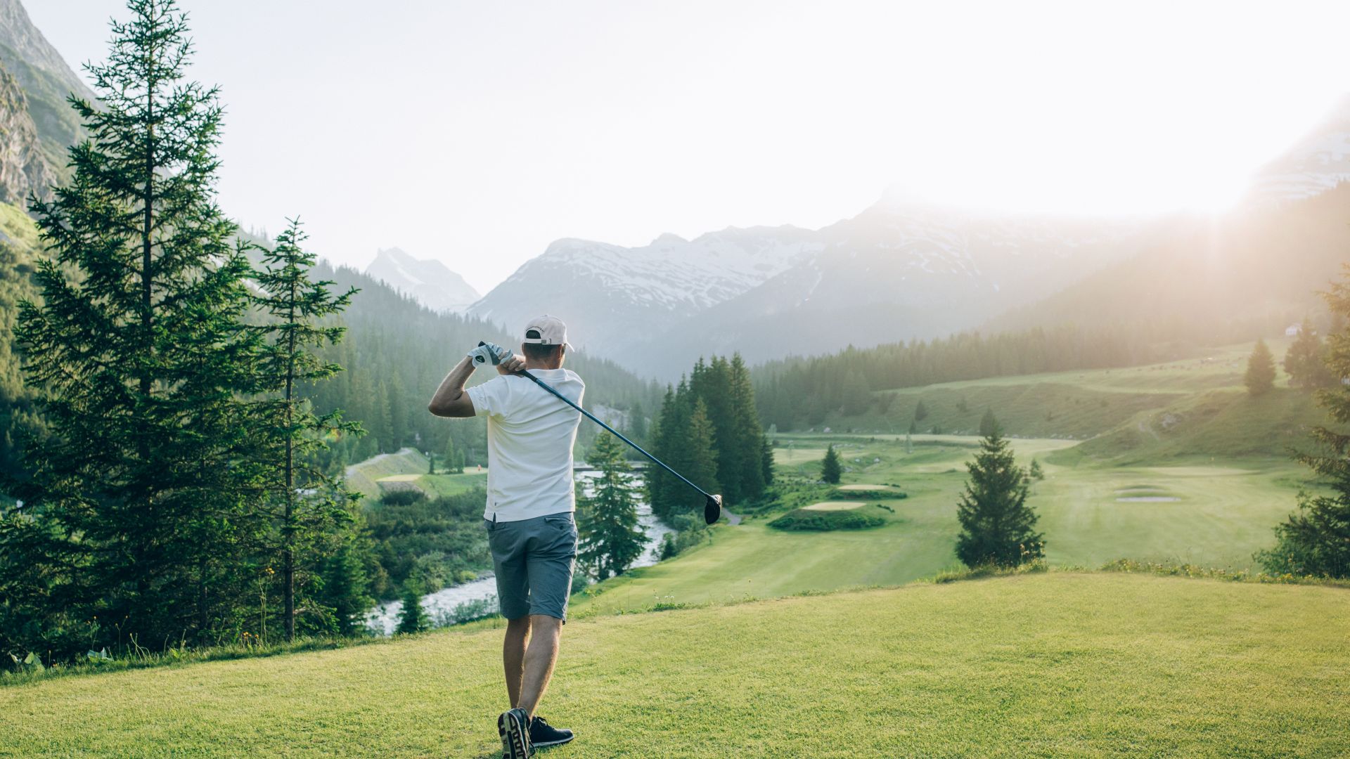 Golfer schlägt Golfball ab und blickt über den Golfplatz in Zug