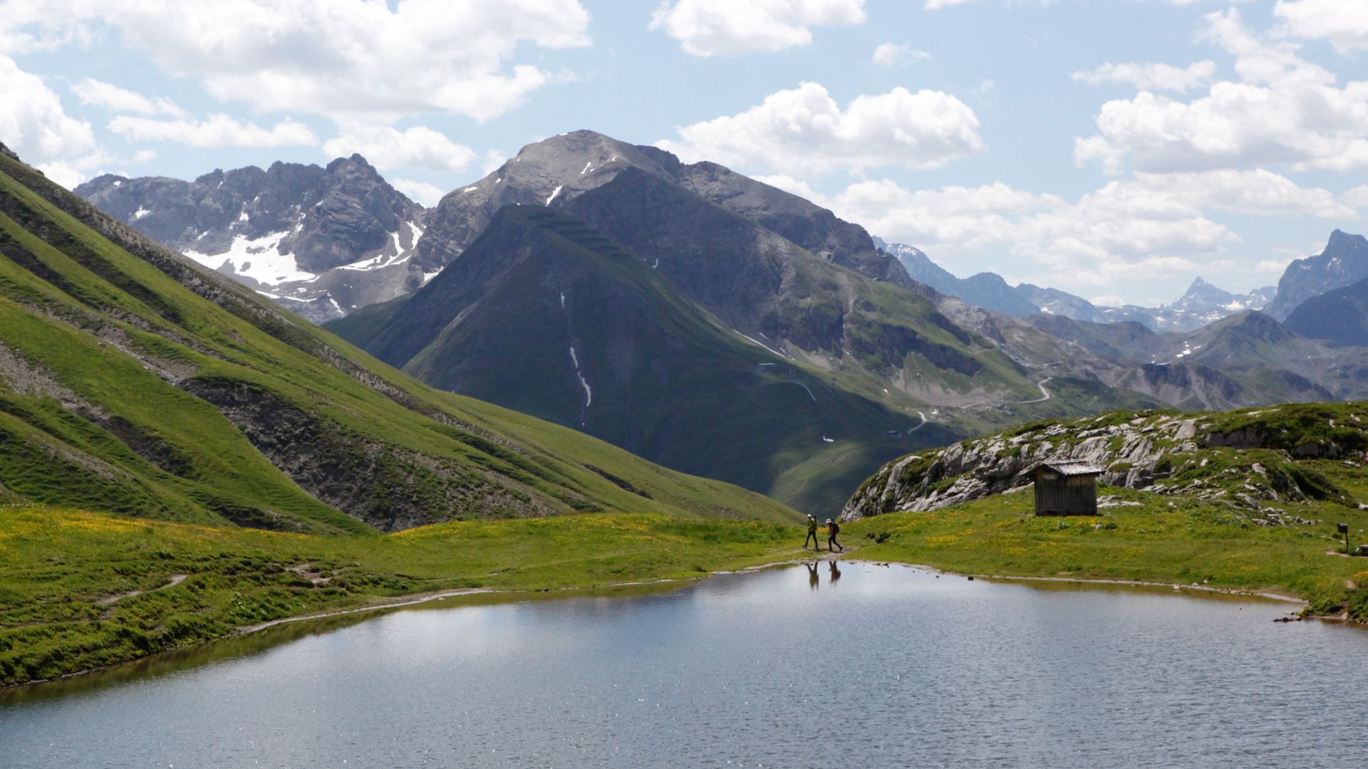 Blick über den Monzabonsee auf ein weitläufiges Bergpanorama