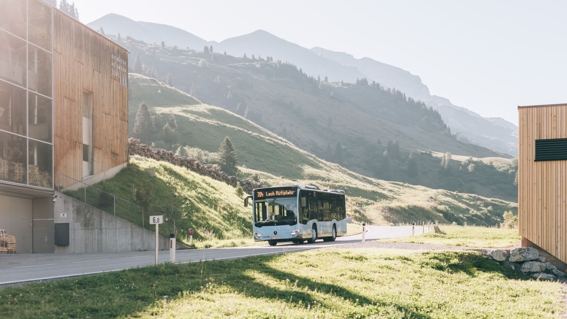 Blauer Ortsbus fährt im Sommer an der Hauptstraße von Zürs nach Lech