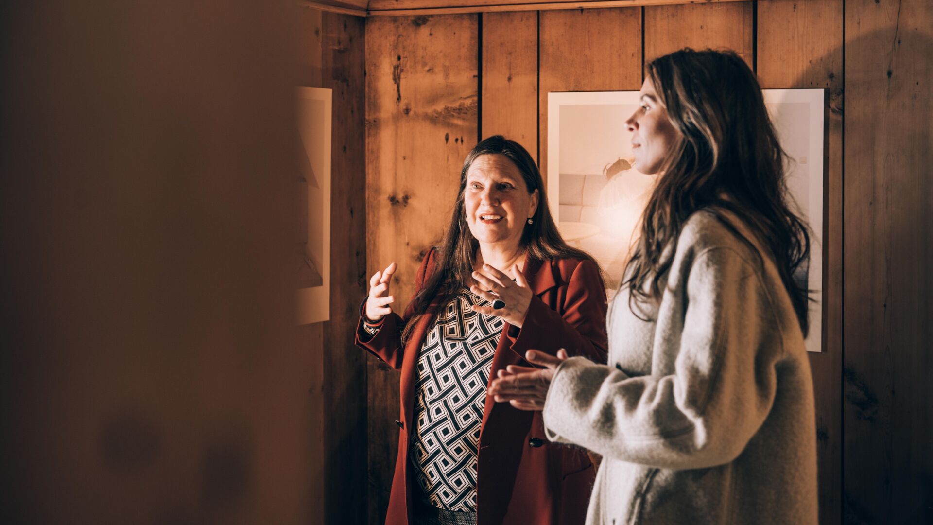 eine Dame hört gespannt bei der Führung im Lechmuseum zu, im Hintergrund sieht man ein Gemälde an einer Holzwand
