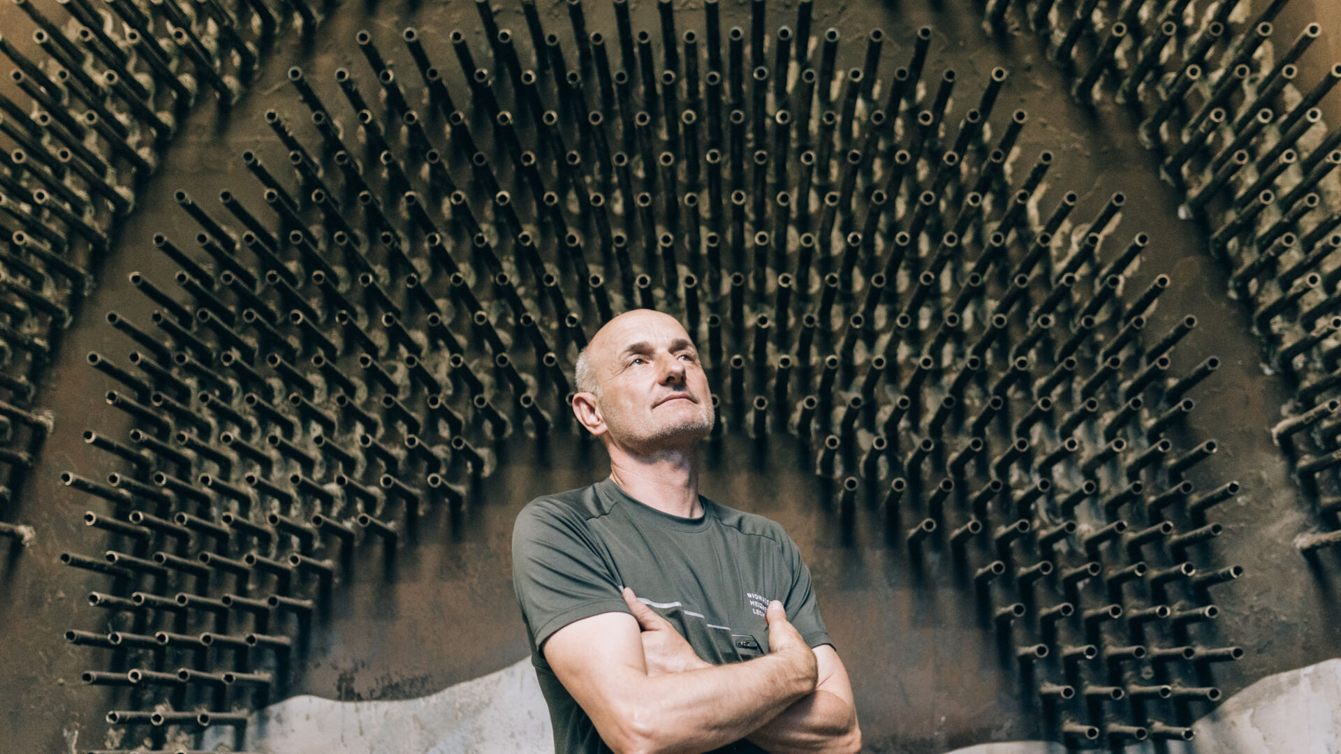 Franz Josef Schmutzer vor einer Wand im Biomasseheizwerk Lech mit seinem Denkerblick 