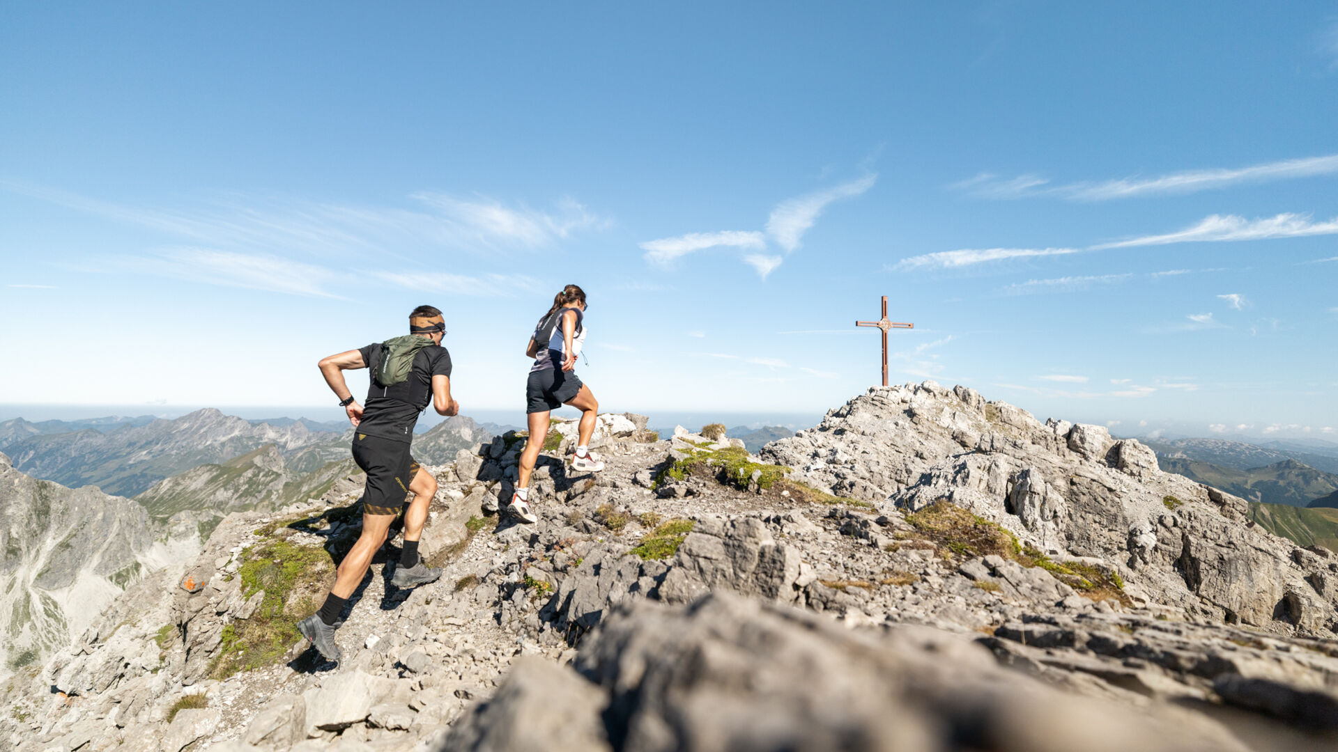 Zwei Trailrunner laufen die letzten Meter bis zum Gipfelkreuz der Mohnenfluh