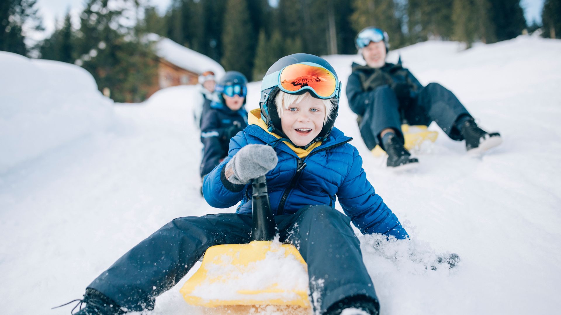 eine Familie rodelt voller Freude mit dem Zipfelbob über die Rodelbahn in Lech Zürs