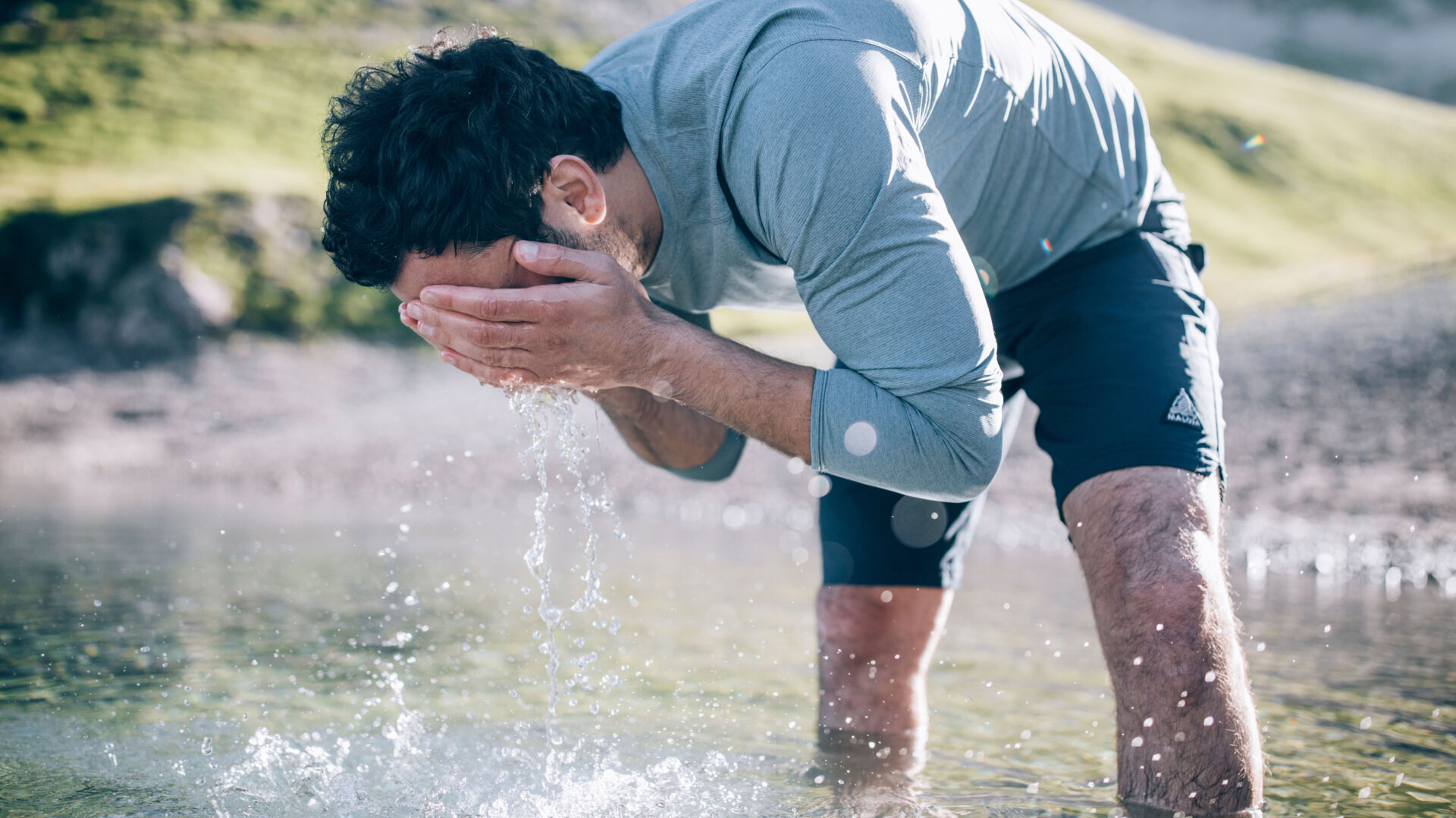 Wanderer steht bis zu den Knien im klaren Wasser des Butzensees und wäscht sich zur Erfrischung das Gesicht