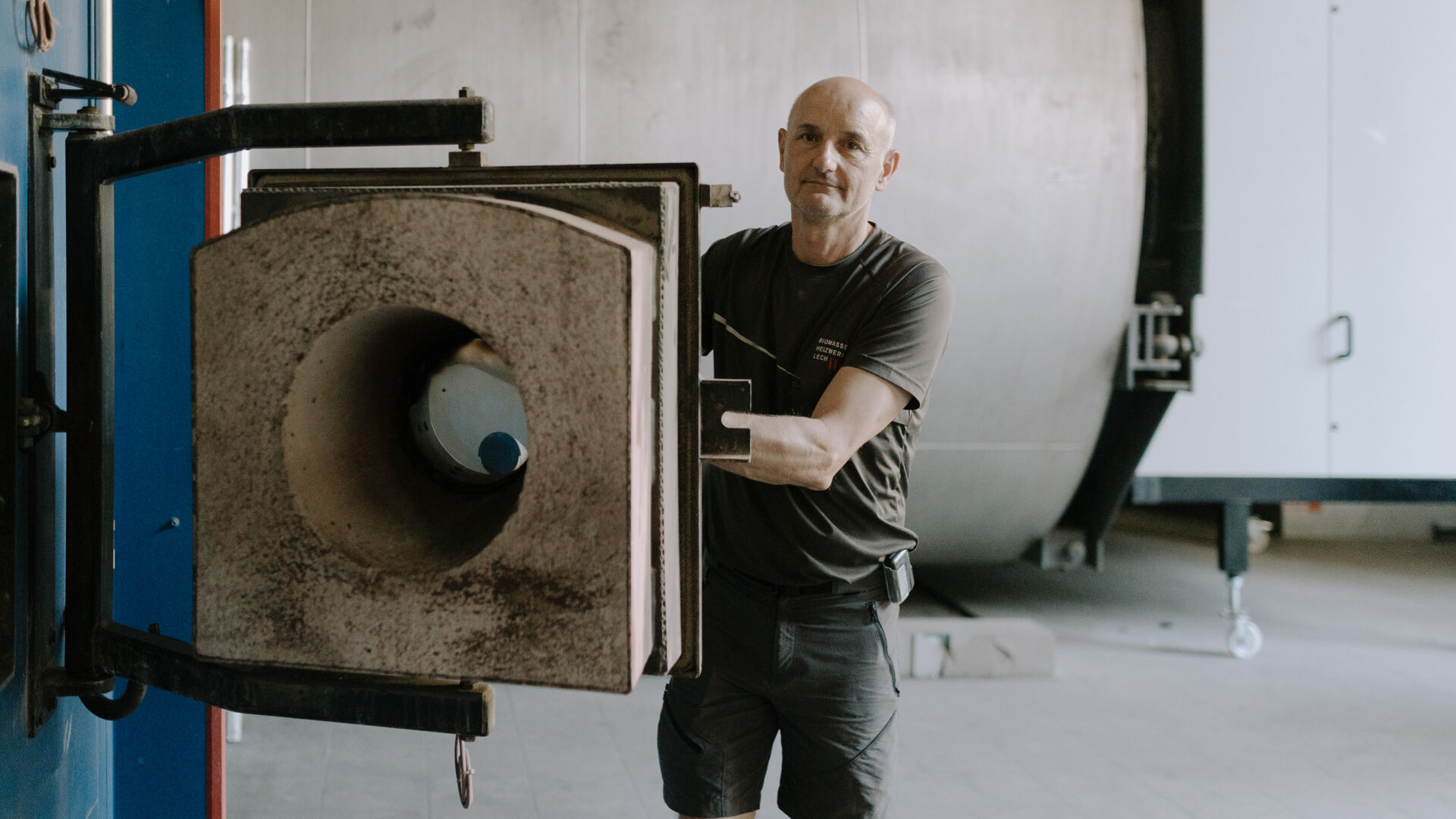 Der Leiter des Biomasseheizwerkes in Lech steht vor der Öffnung des Ofens in dem die Holzschnitzel verbrannt werden
