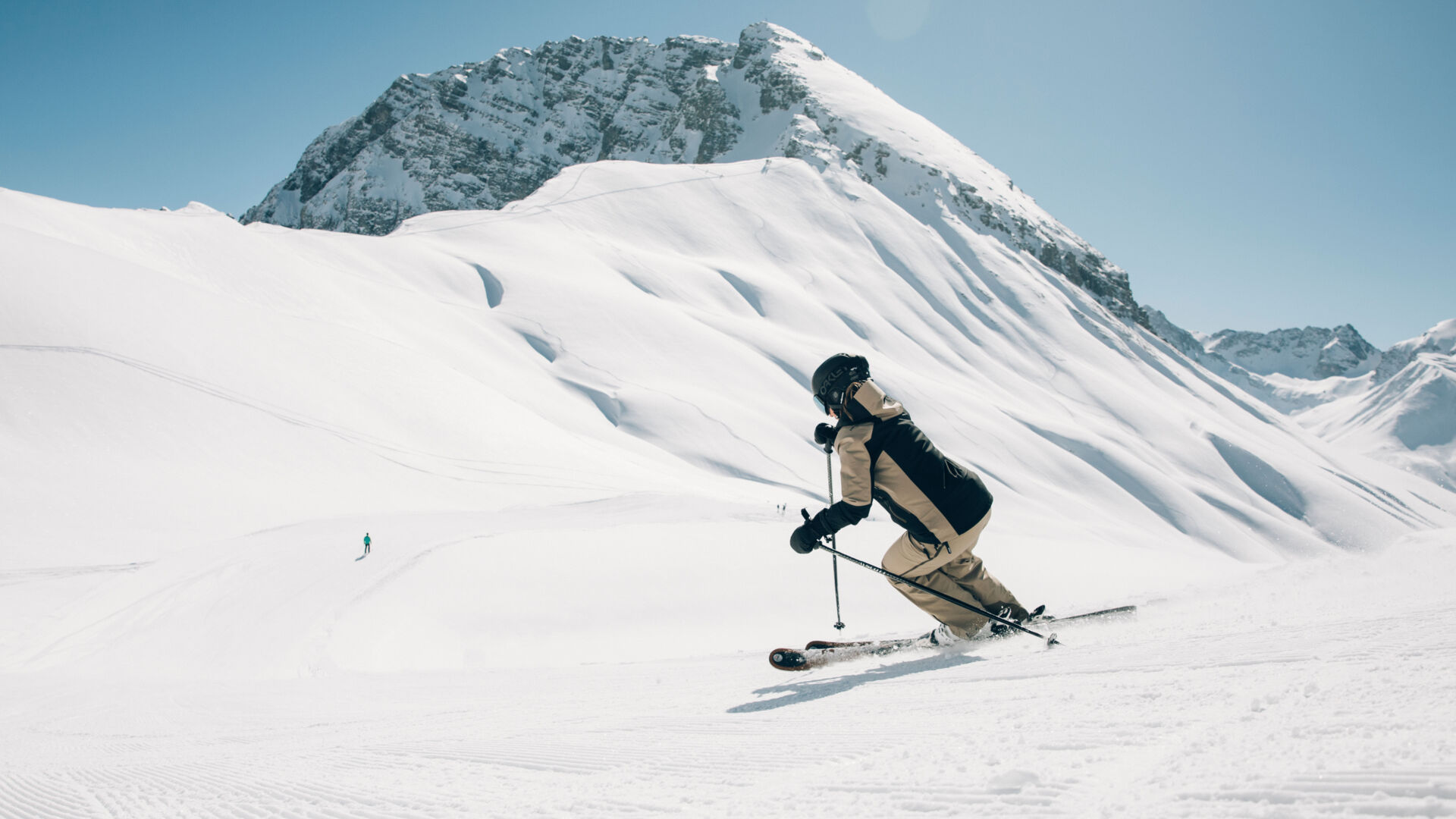 eine Skifahrerin fährt über die frisch präparierte Abfahrt mit Aussicht auf ein traumhaftes Bergpanorama