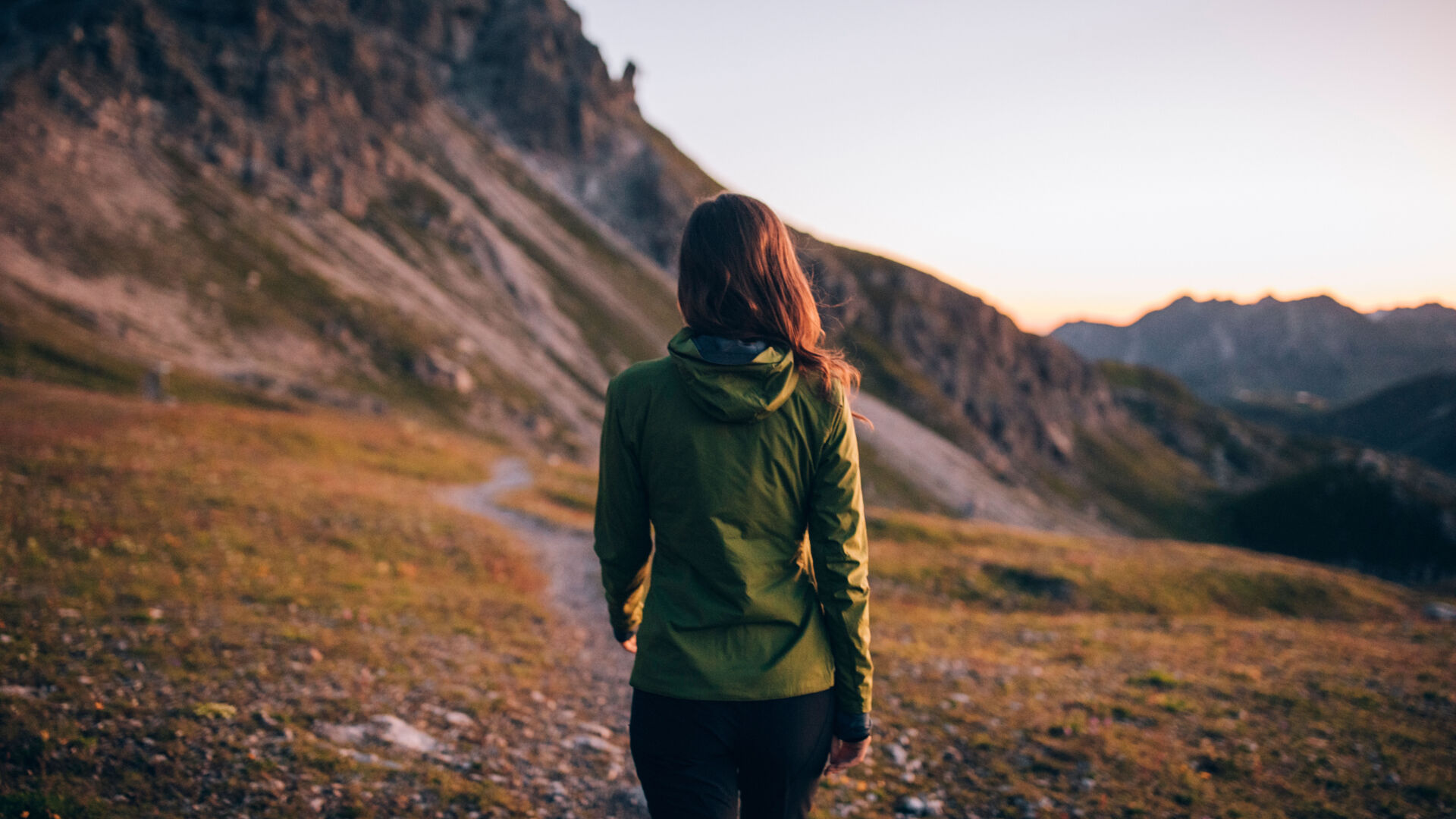 Frau wurde von hinten fotografiert wie sie an einem Steig bei Sonnenaufgang wandert