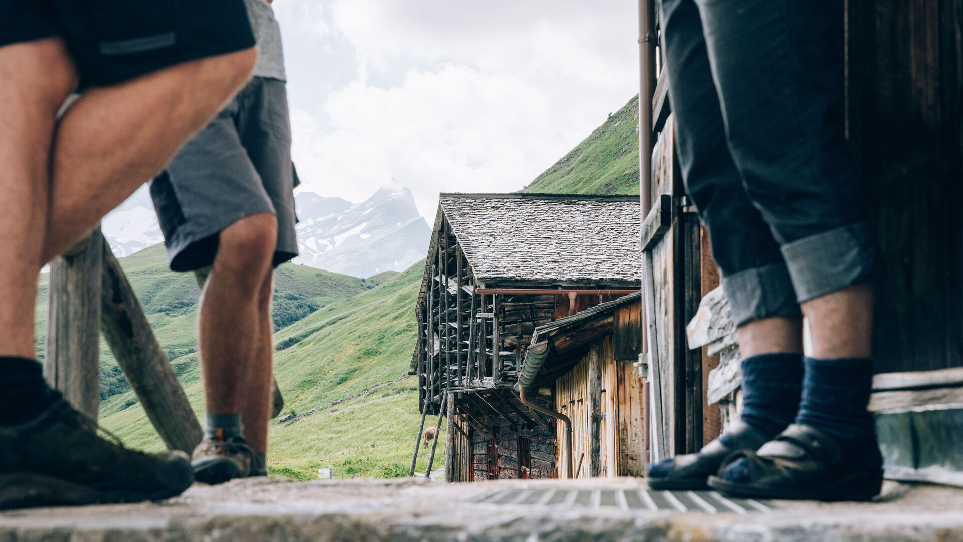 Blick auf die Füße mehrerer Personen wie sie gerade auf einer urigen Terrasse in Bürstegg stehen