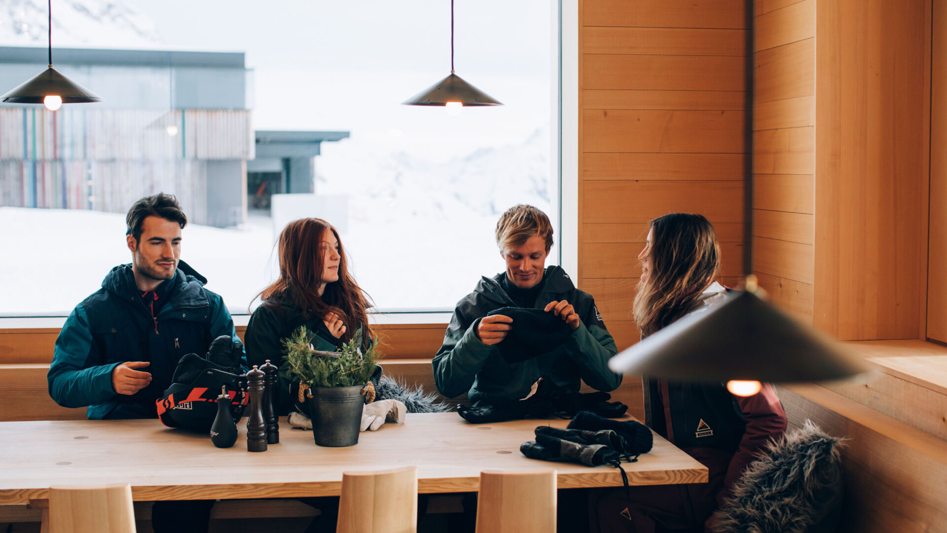 vier Freunde ziehen ihre Skiausrüstung beim Einkehren in der Skihütte aus