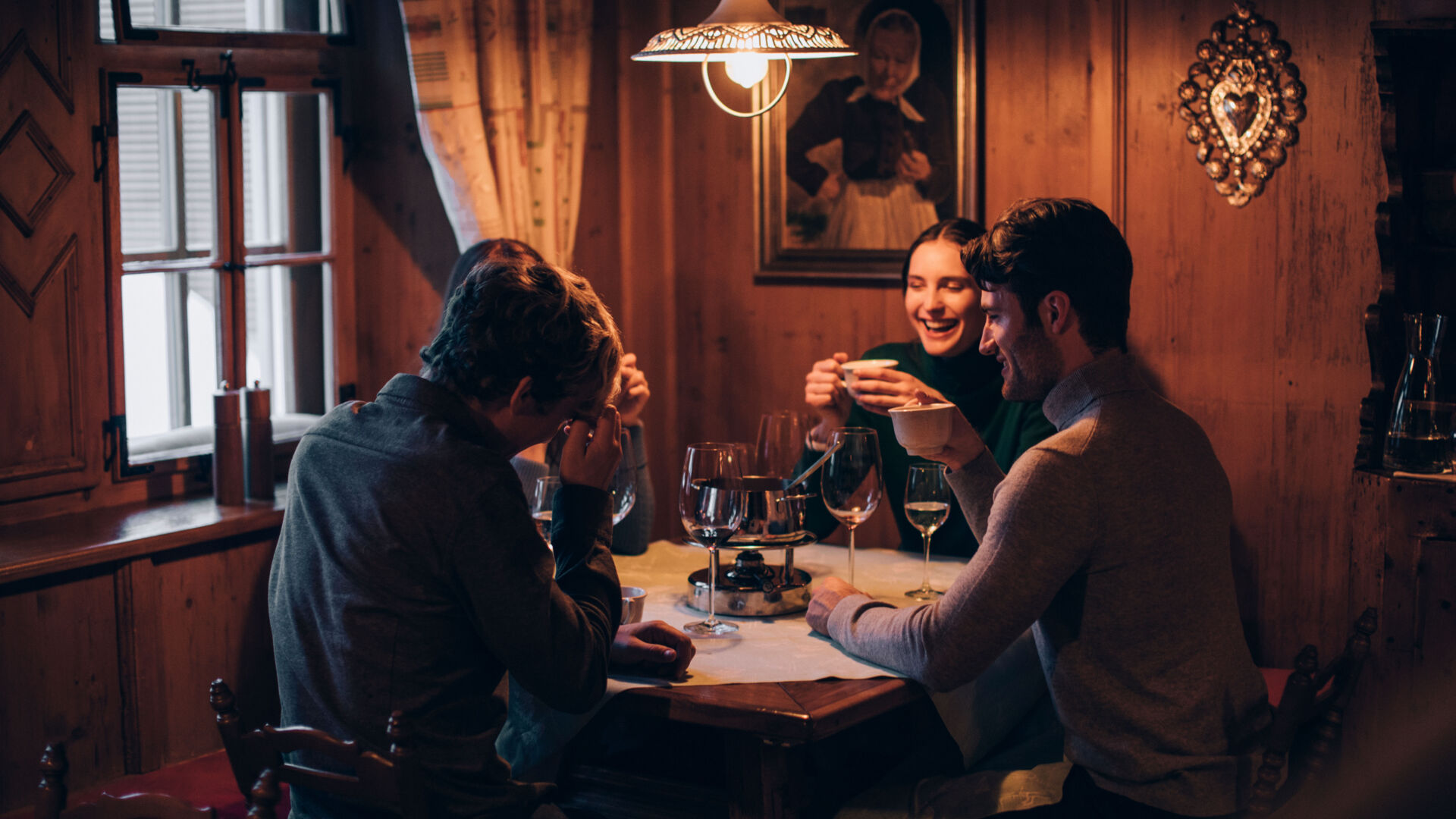 Freunde genießen gemeinsam ein gemütliches Fondue-Essen bei Wein an einem runden Tisch