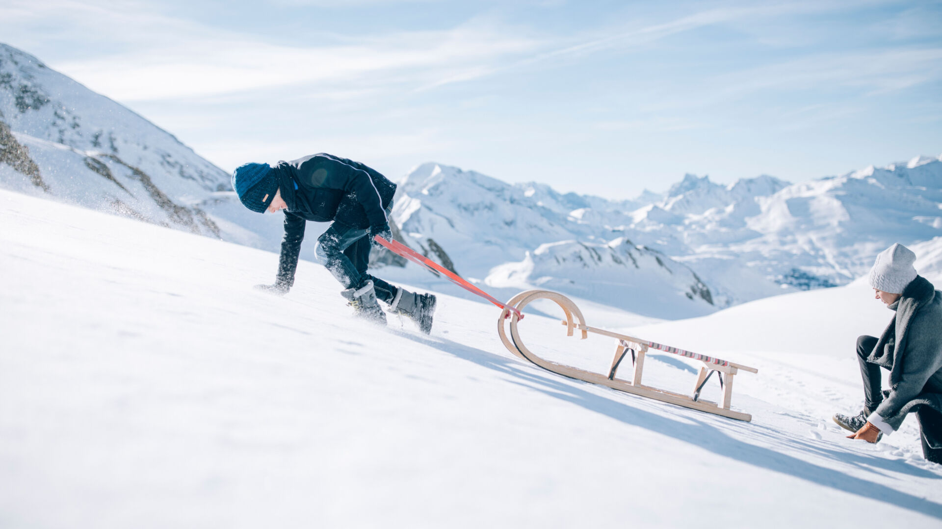Familie beim Winterwanderweg am Rüfikopf in Vorarlberg zieht den Schlitten den Berg hoch 