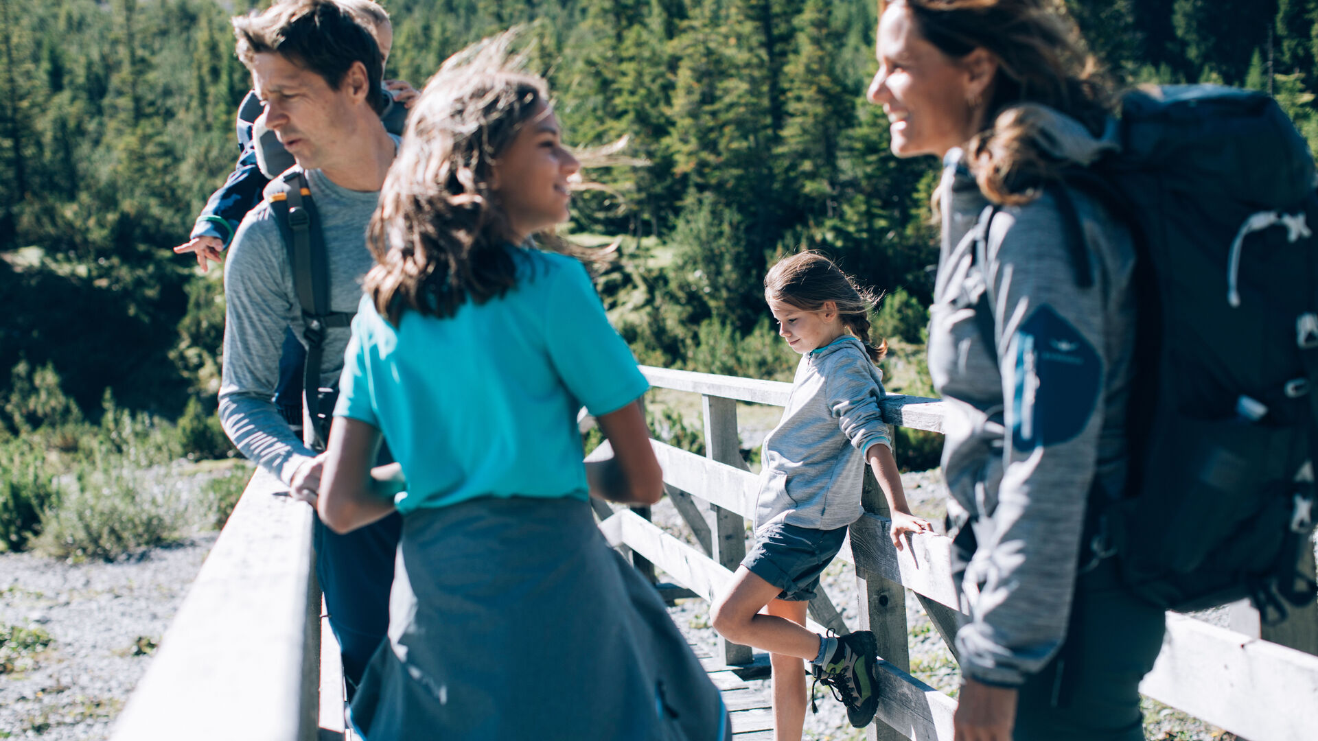 Eine Familie mit zwei Kinder in Wanderbekleidung macht Pause auf einer Bruecke die ueber den Lech fuehrt